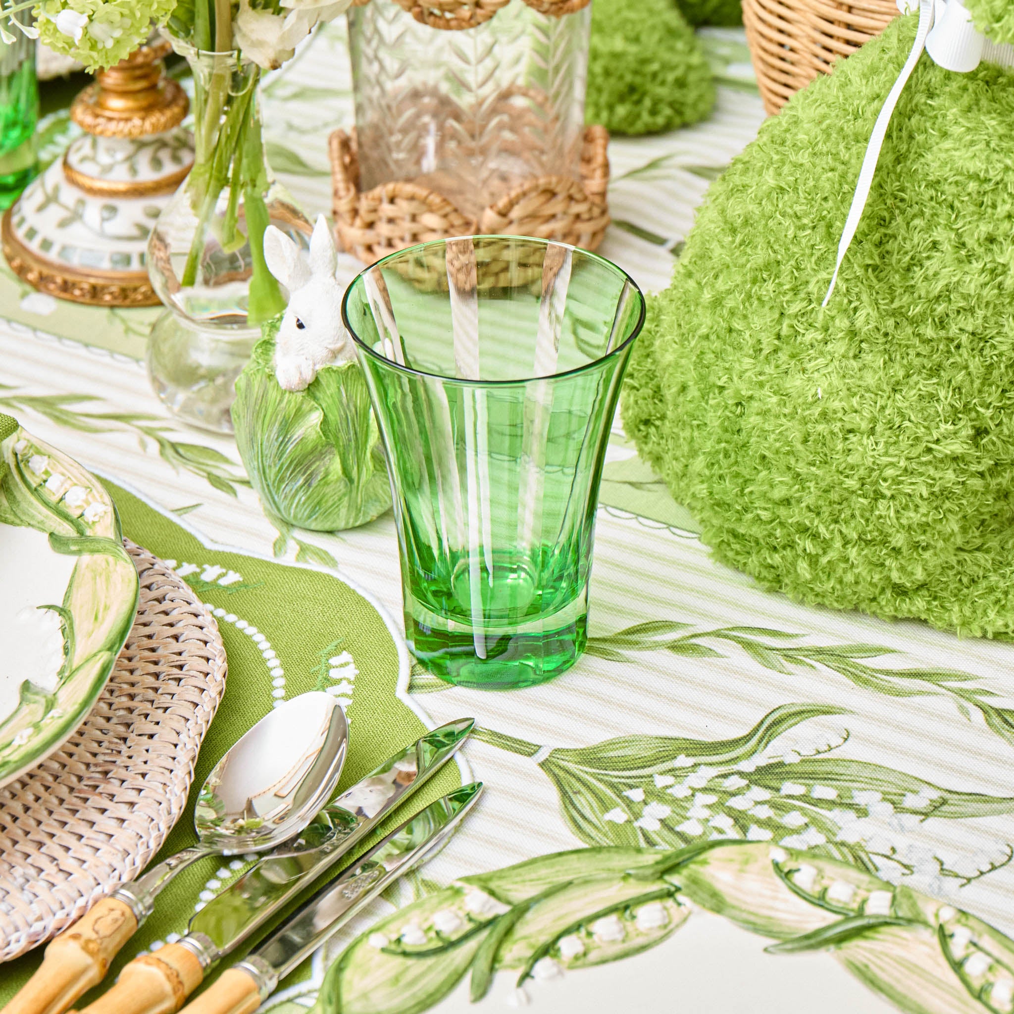 Green glassware and table setting with decorative elements on a tablecloth.
