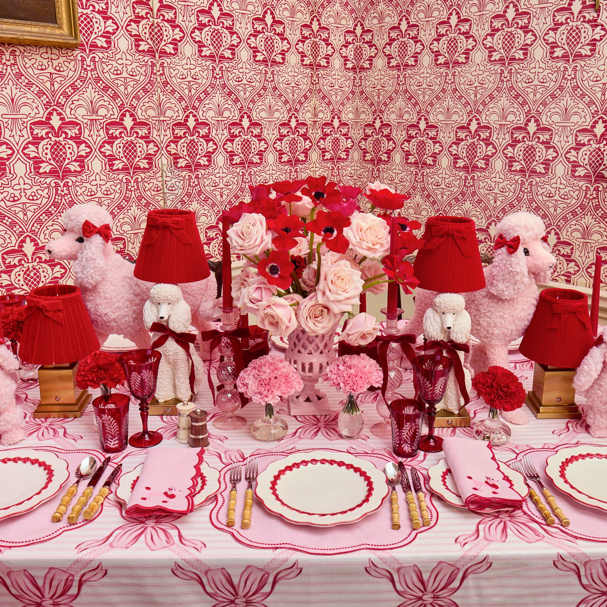Decorative table setting with red and white theme, including poodles, lamps, and flowers.