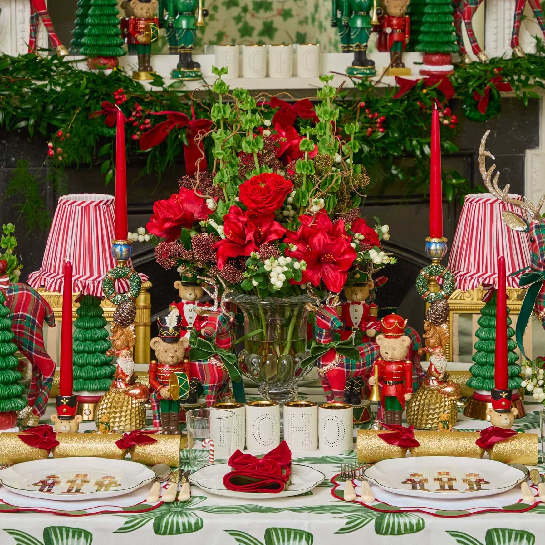Decorative Christmas table setting with red and green accents, including candles, flowers, and ornaments.