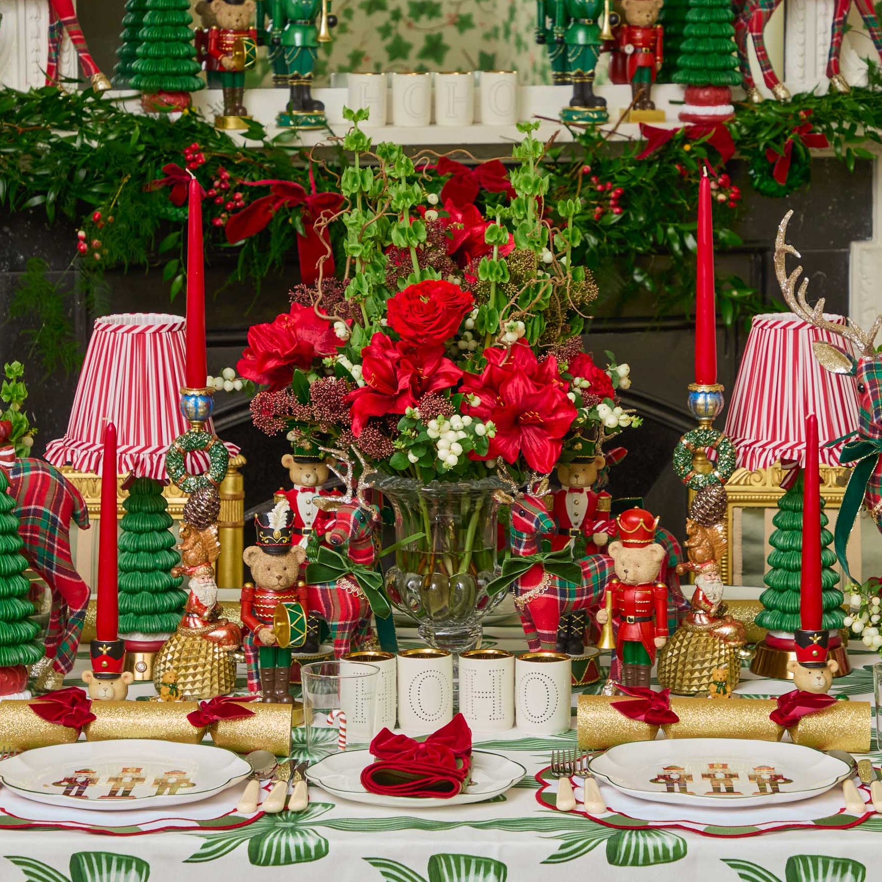 Decorative Christmas table setting with red and green accents, including candles, flowers, and ornaments.