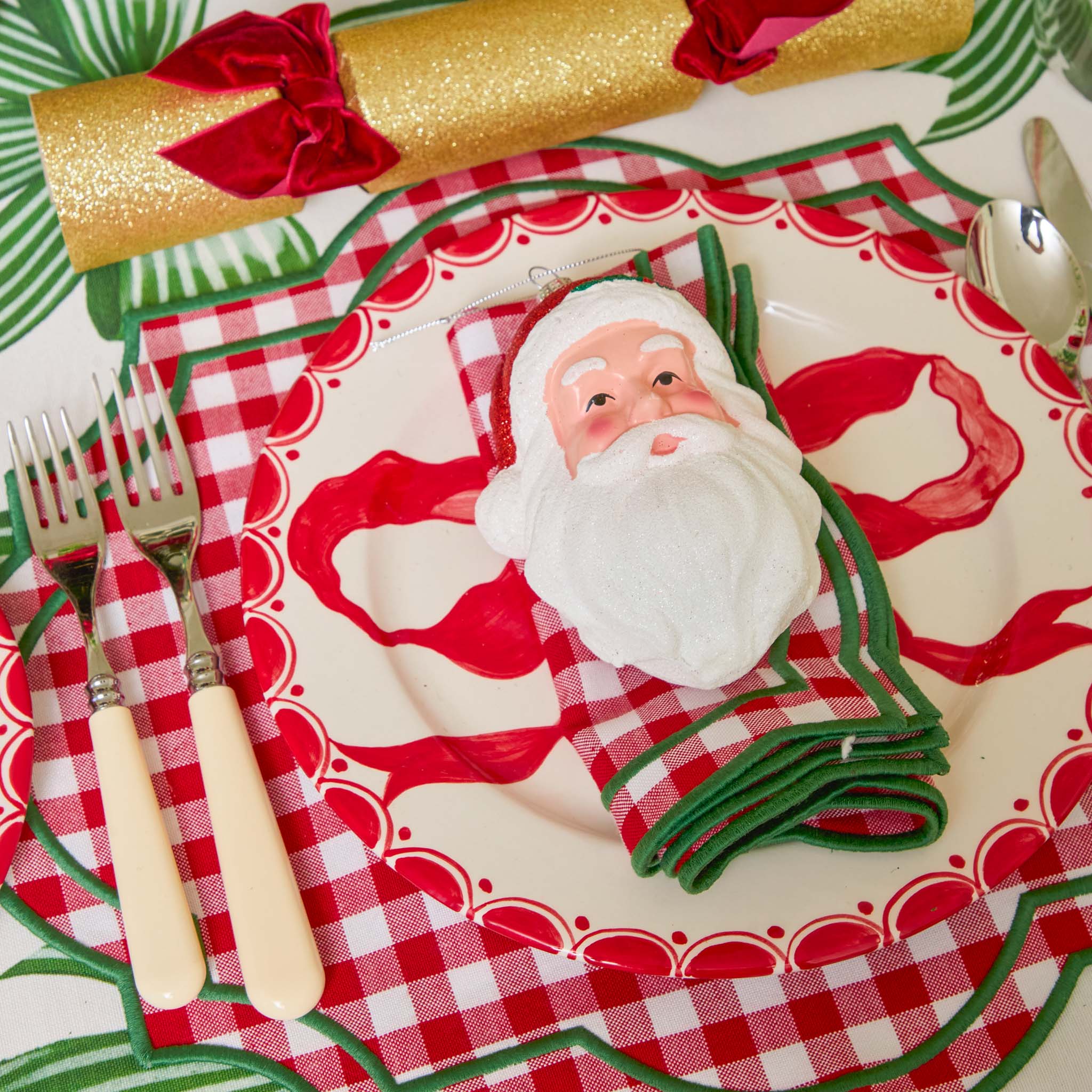 Christmas-themed place setting with Santa Claus design on a plate, cutlery, and napkins.