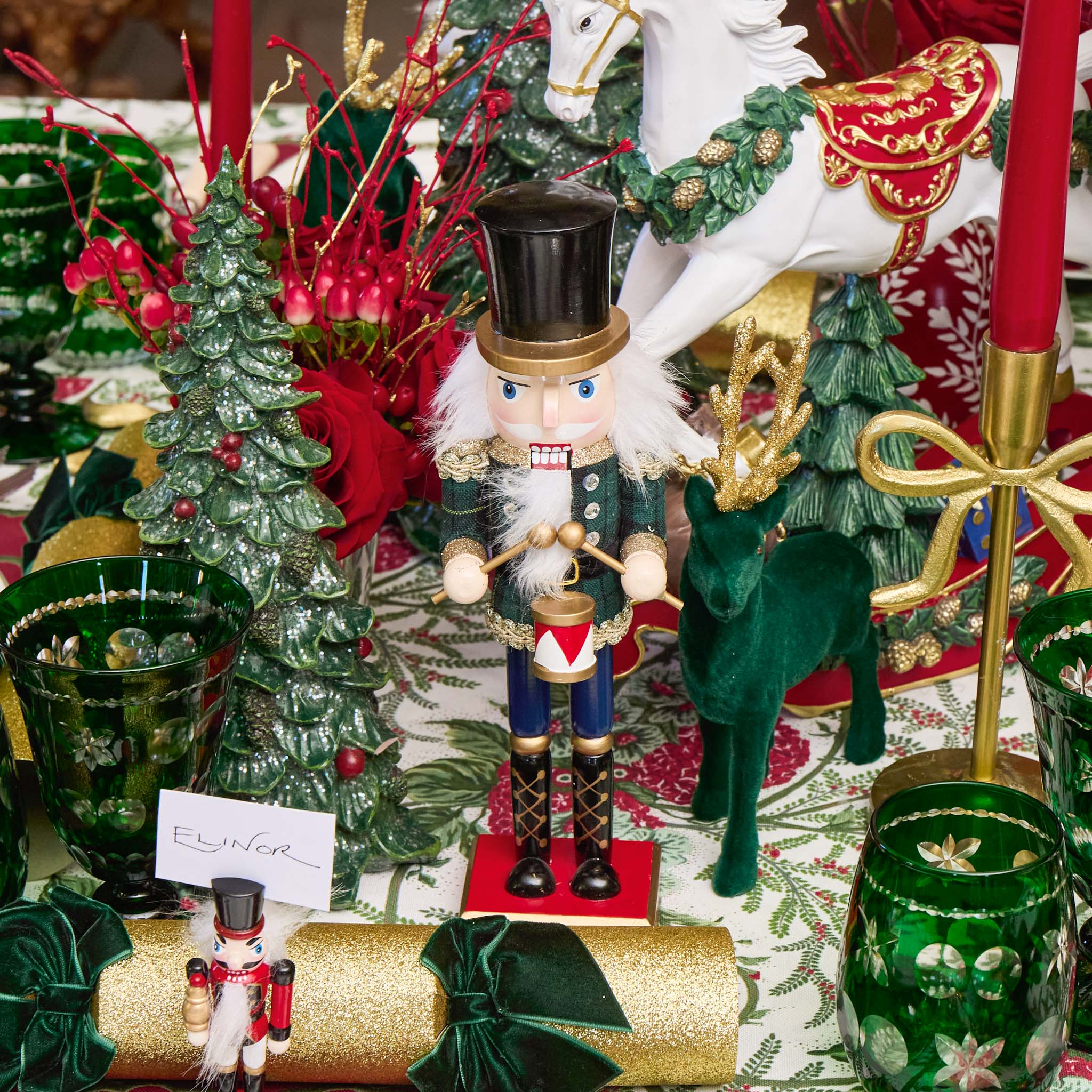Decorative Christmas scene with nutcrackers, trees, and other ornaments on a table.