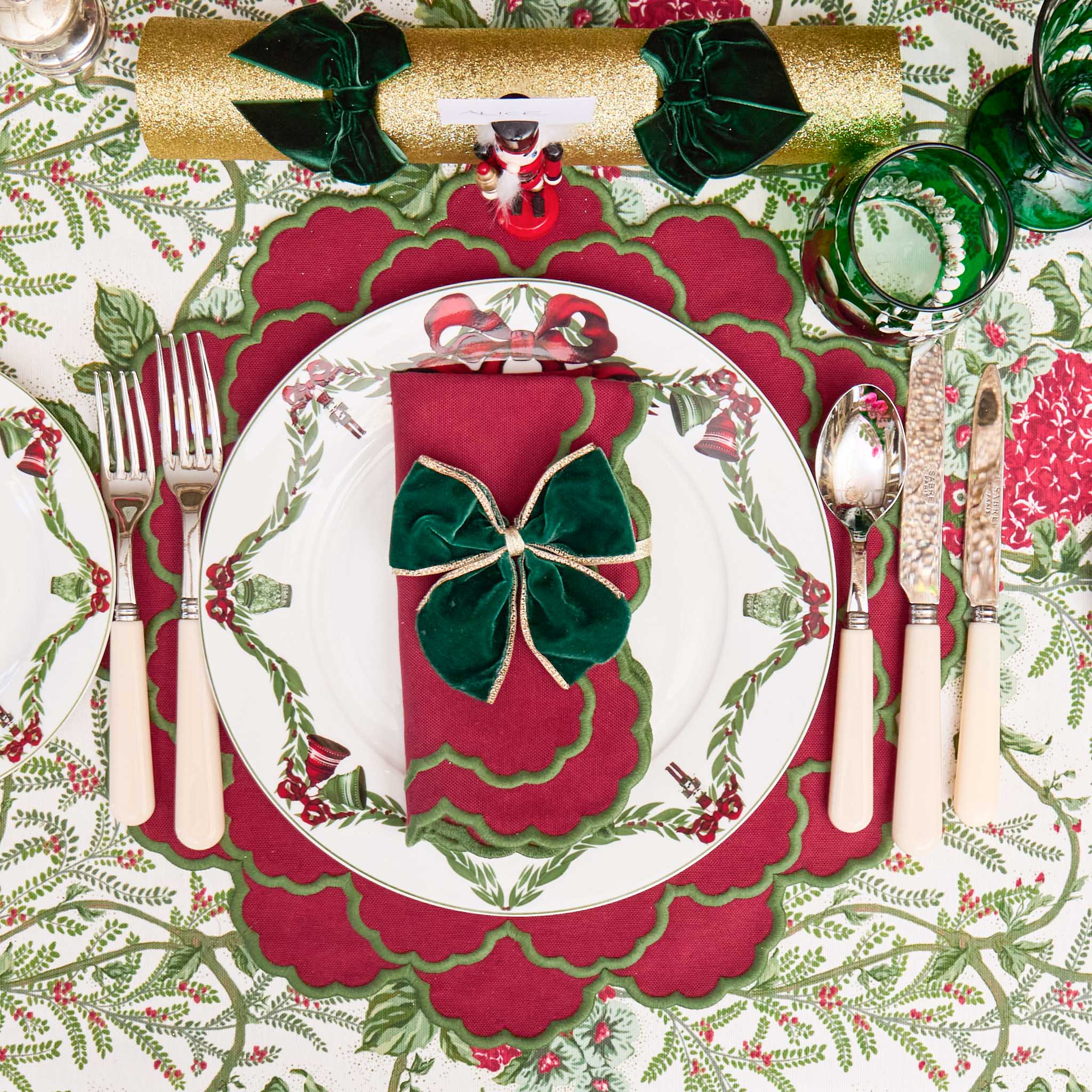 Christmas-themed table setting with red and green decorations, including a bow on a plate.