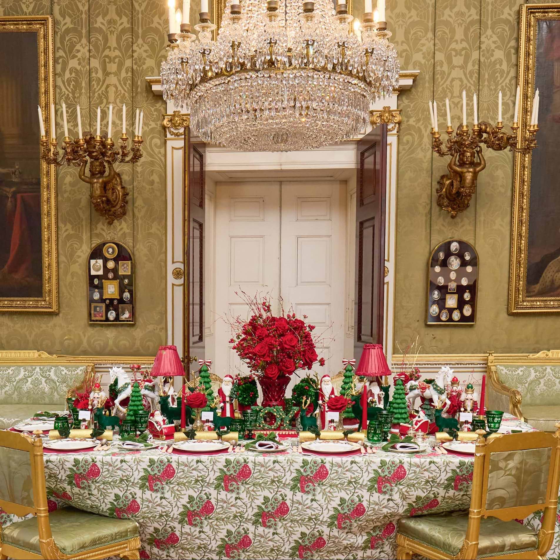 Decorative dining room with a table set for Christmas, featuring a large crystal chandelier and ornate wall decorations.