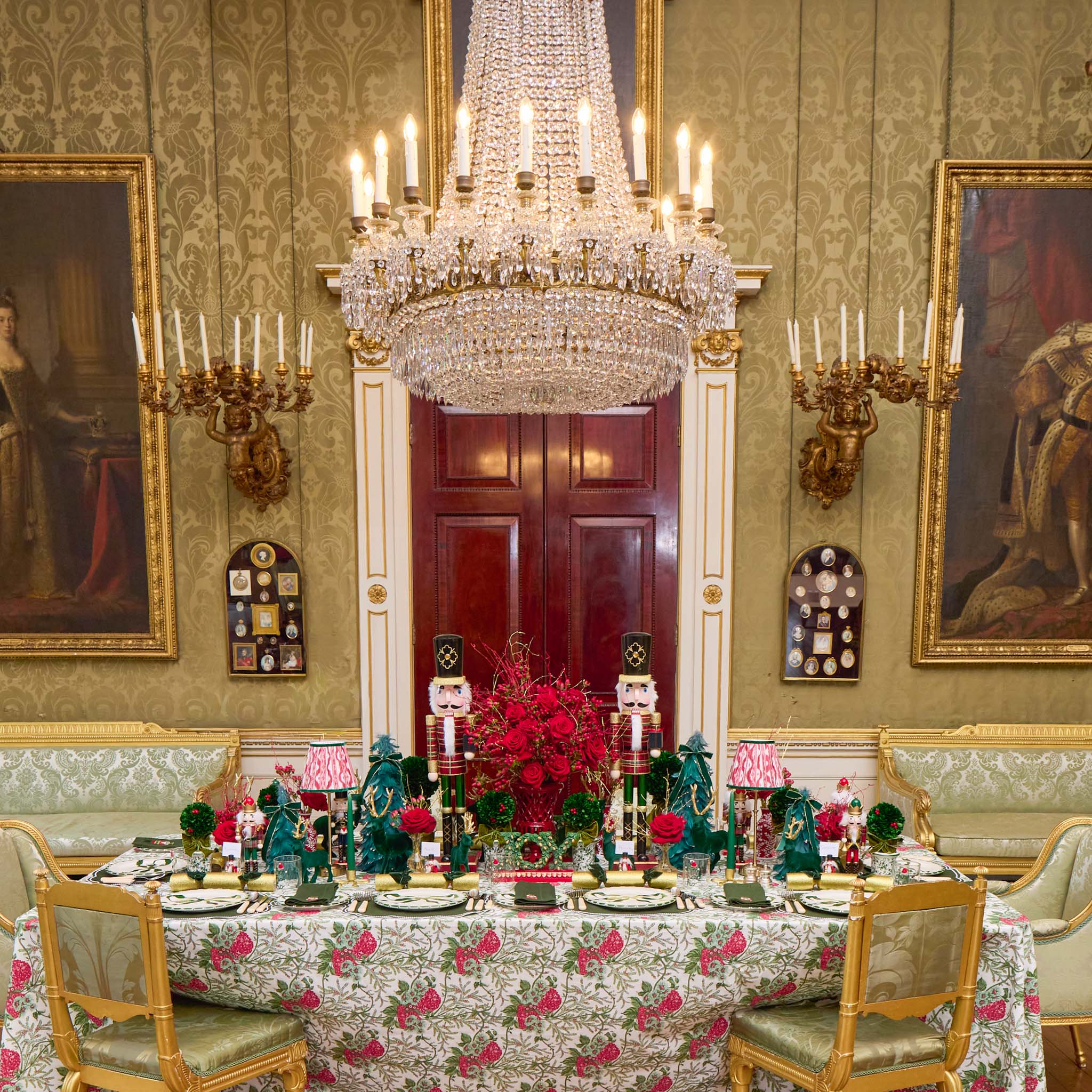 Dining room with ornate chandelier, floral tablecloth, and classical decor.