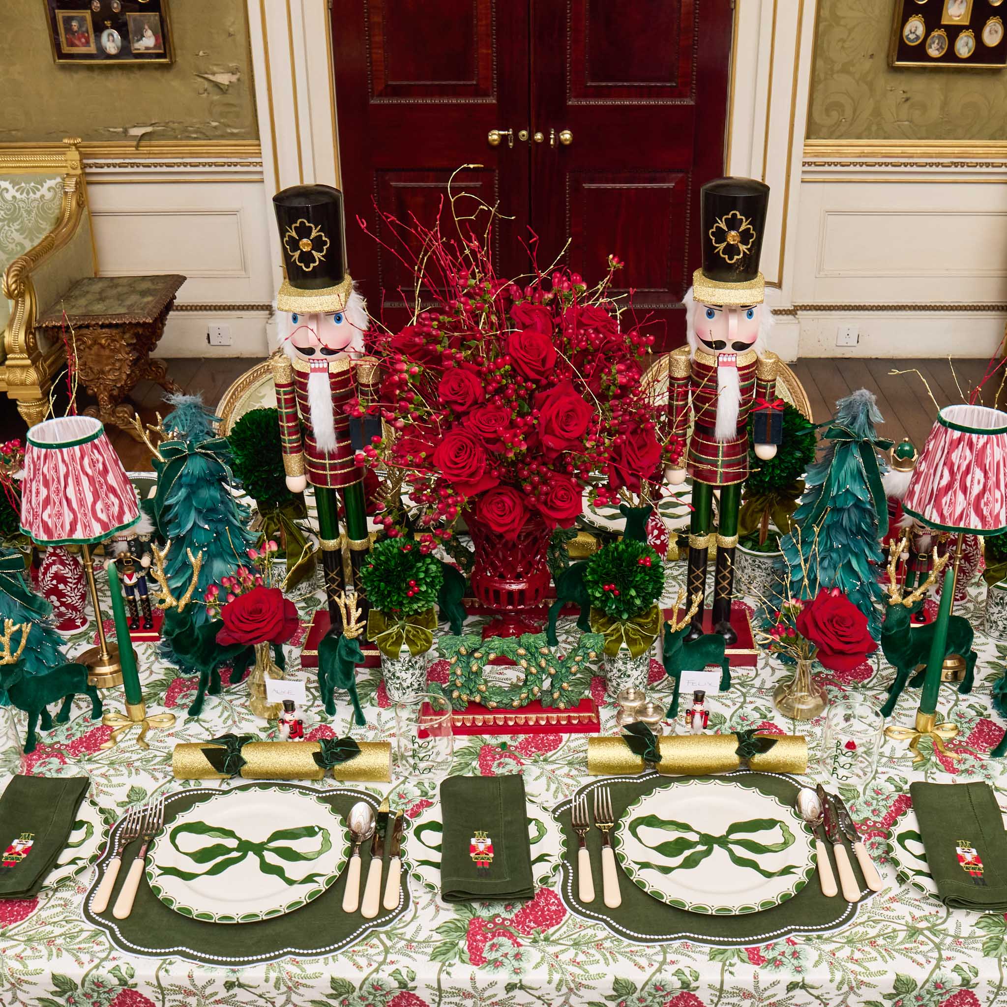 Decorative Christmas table setting with nutcrackers, floral arrangements, and green bow placemats.