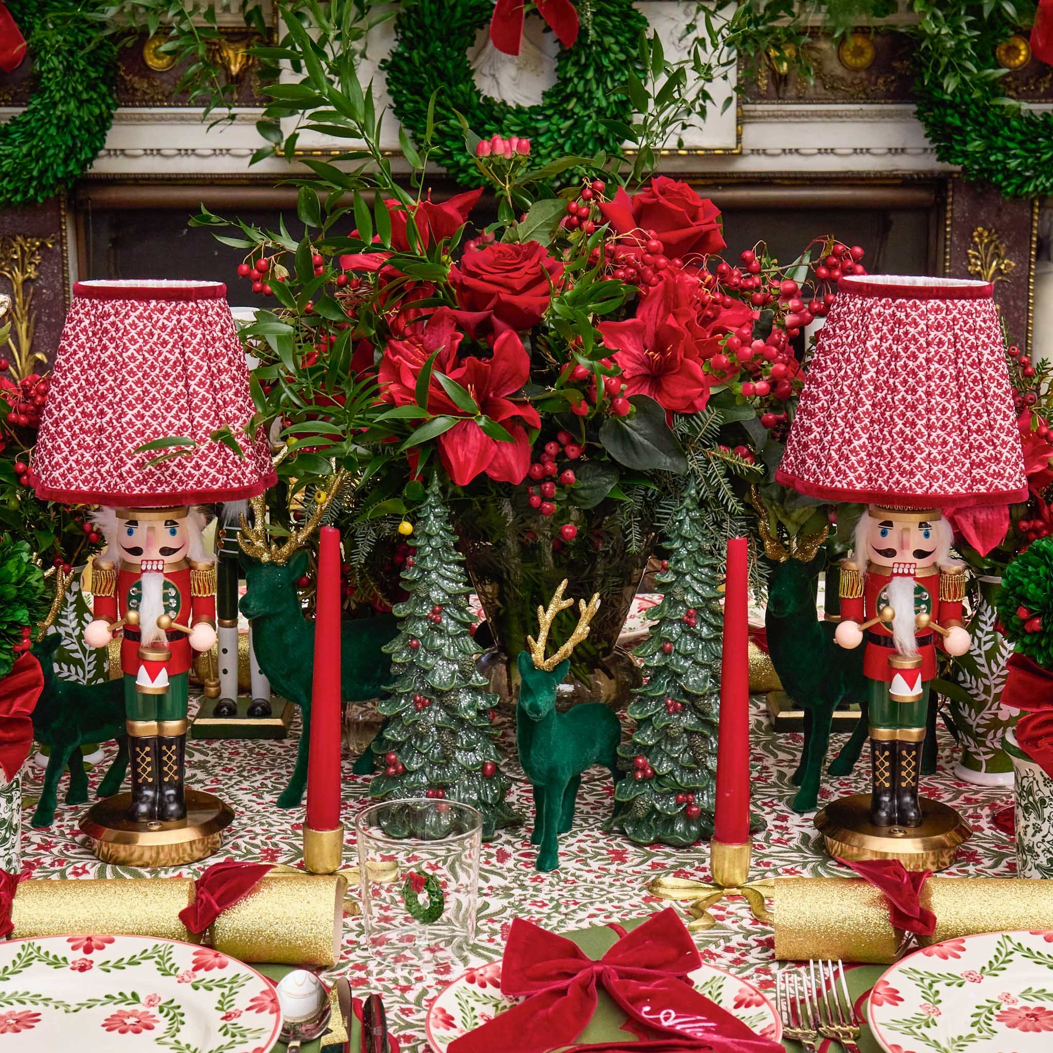 Decorative Christmas table setting with nutcrackers, red candles, and floral arrangements.