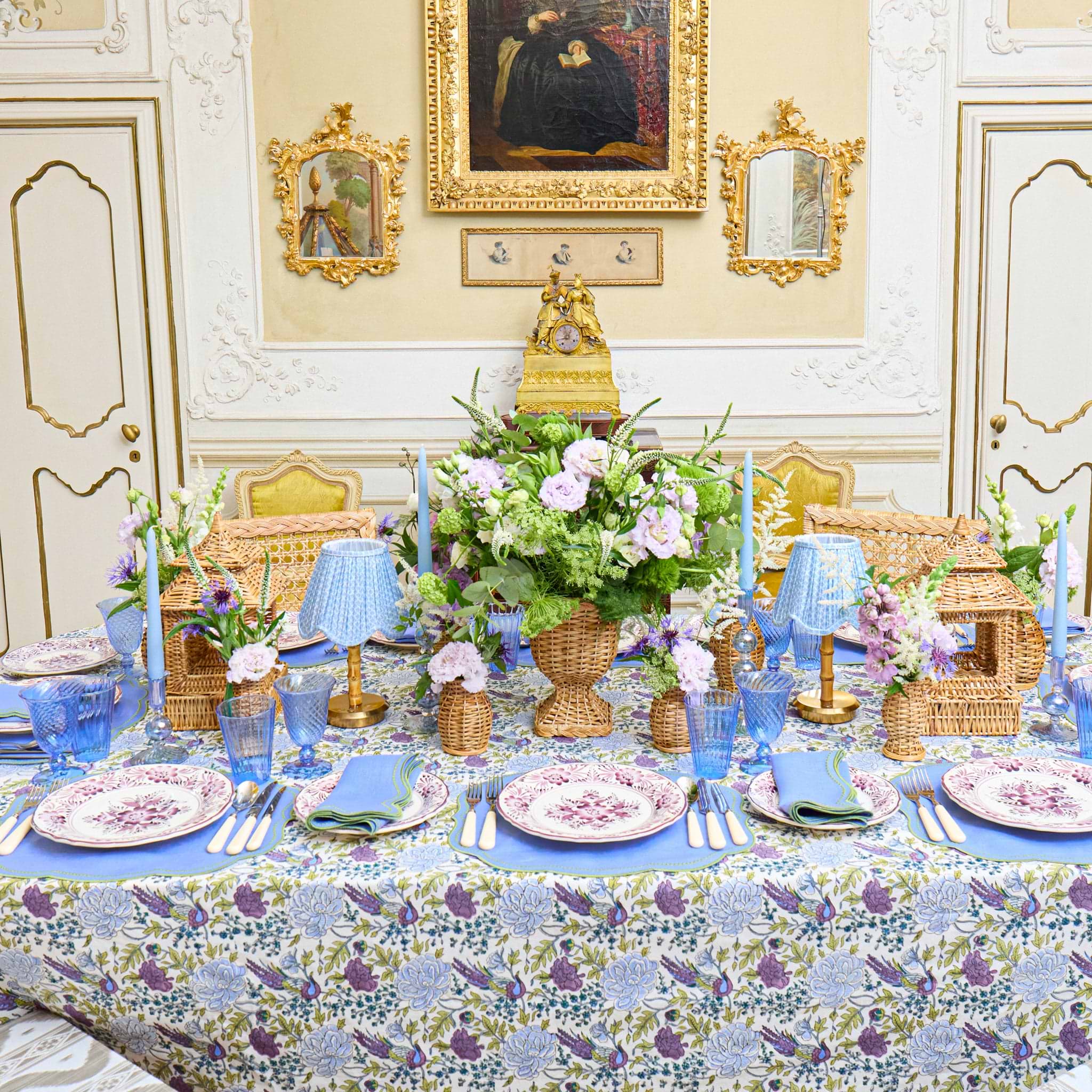 Elegant table setting with floral centerpiece in a decorated room with paintings on the wall.