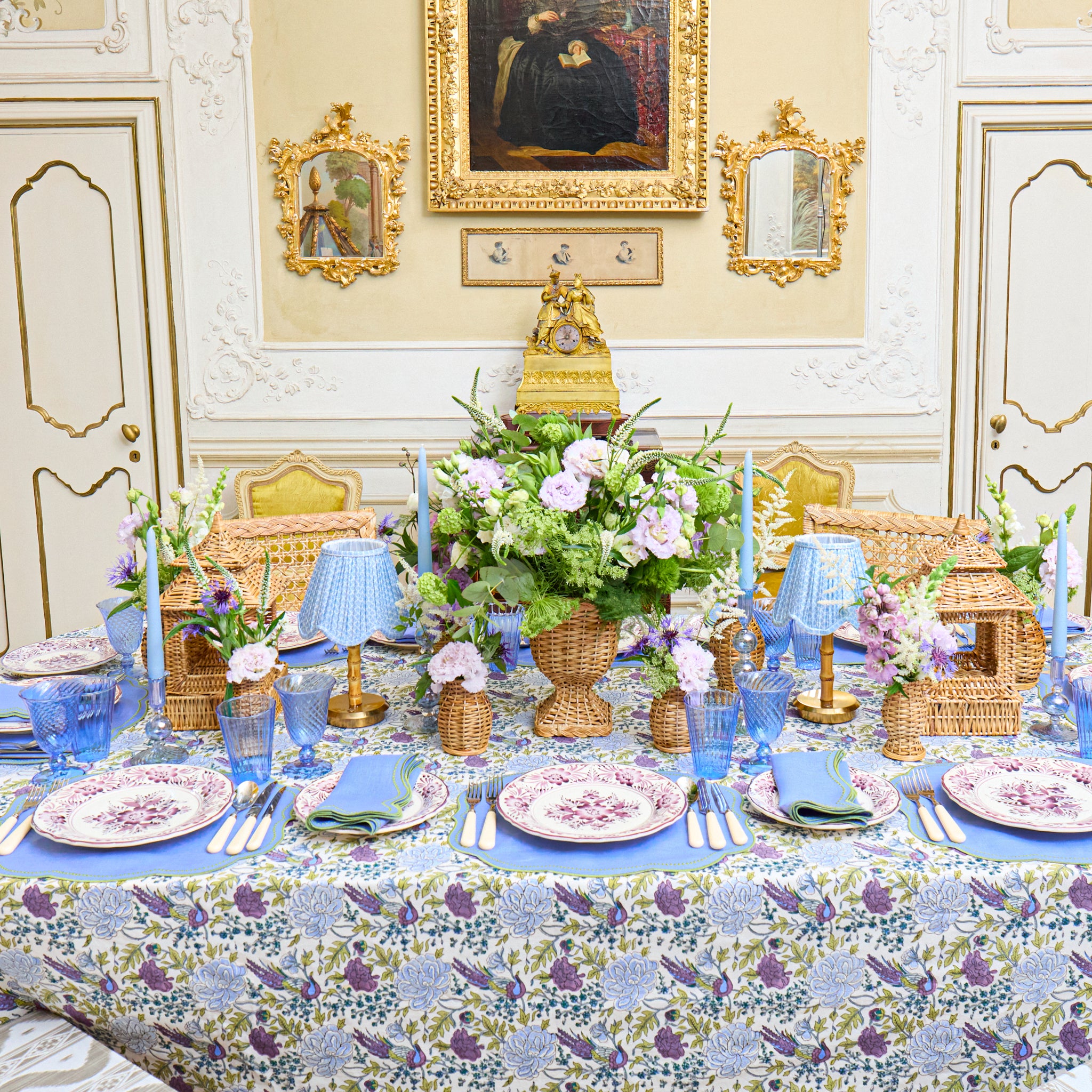 Elegant table setting with floral centerpiece in a decorated room with paintings on the wall.