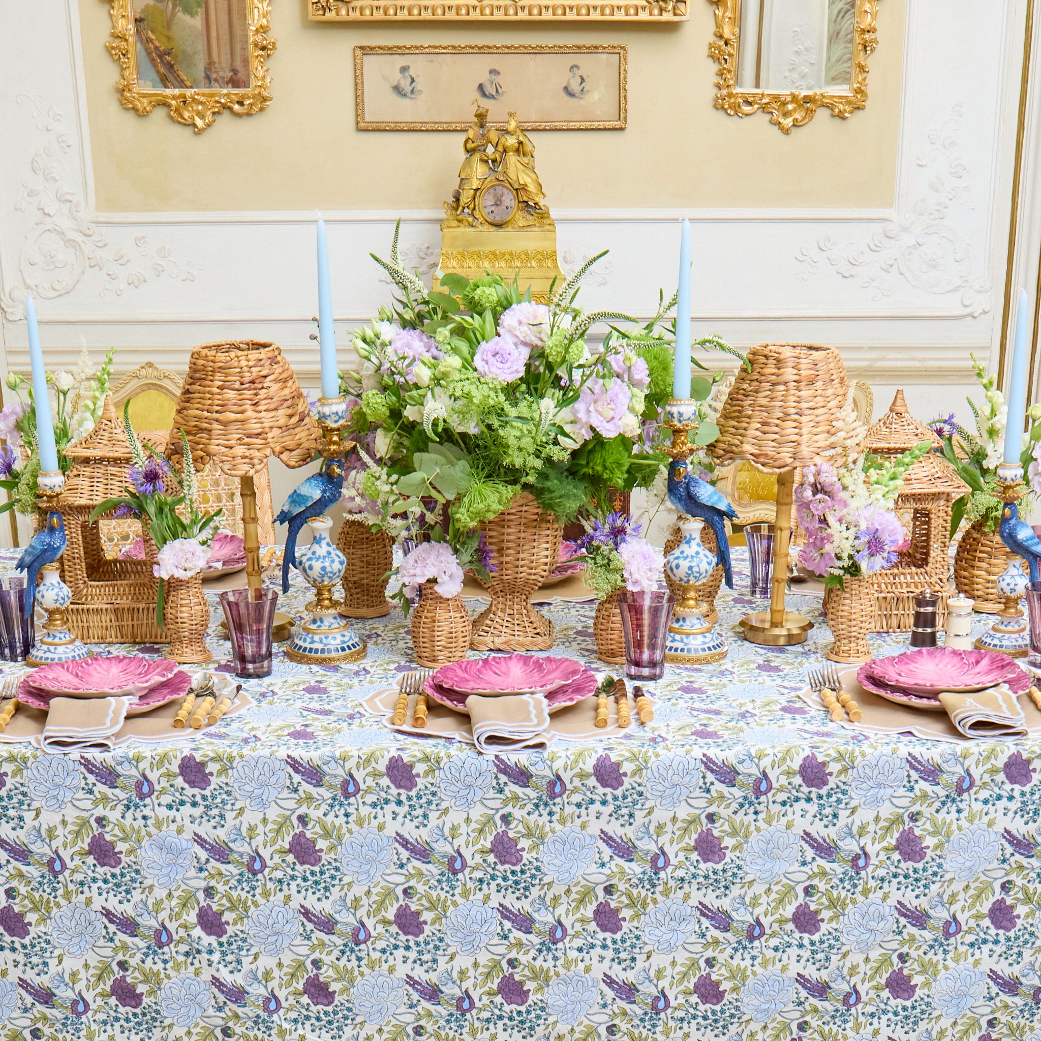 Decorative table setting with floral arrangements, candles, and wicker lanterns.