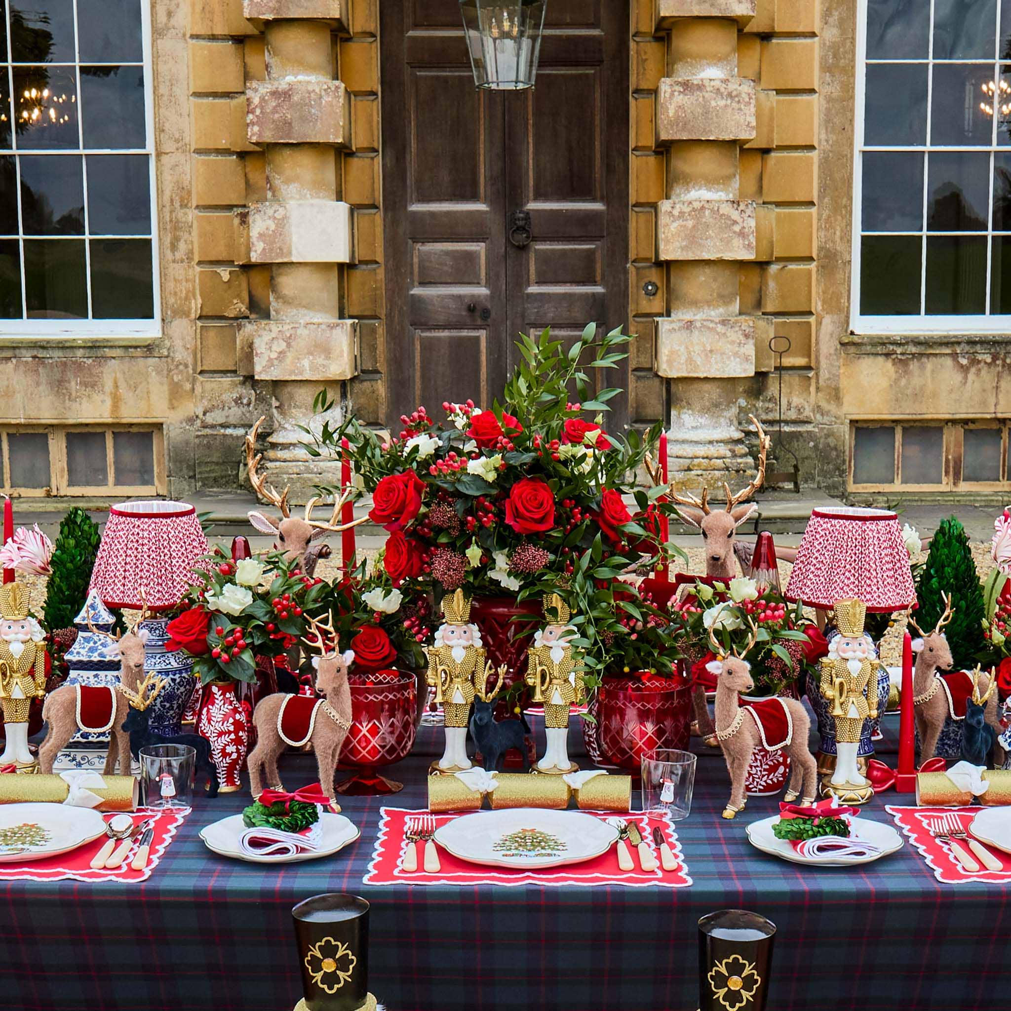 Decorative table setting with red and gold theme in front of a stone building.