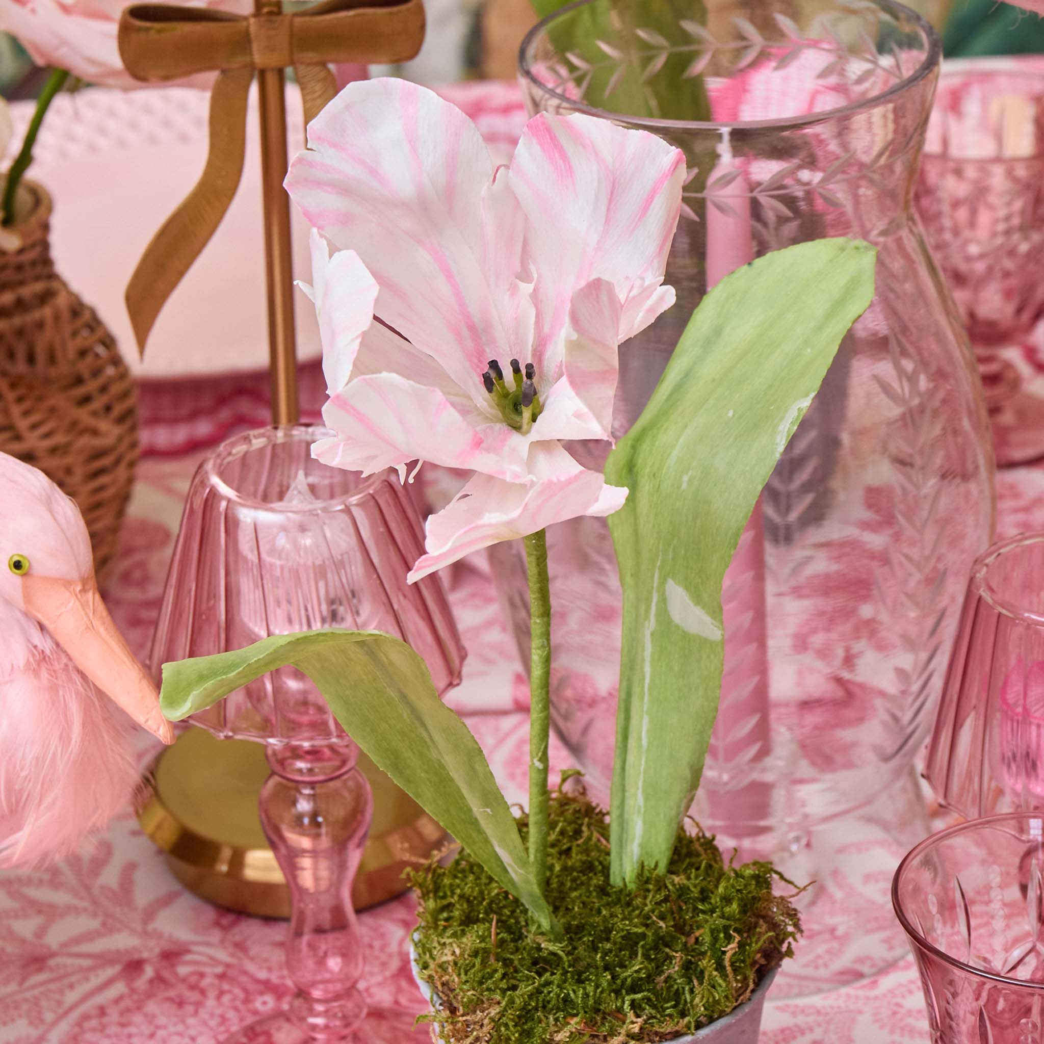 Decorative pink flower arrangement on a table with pink glasses and a flamingo toy.
