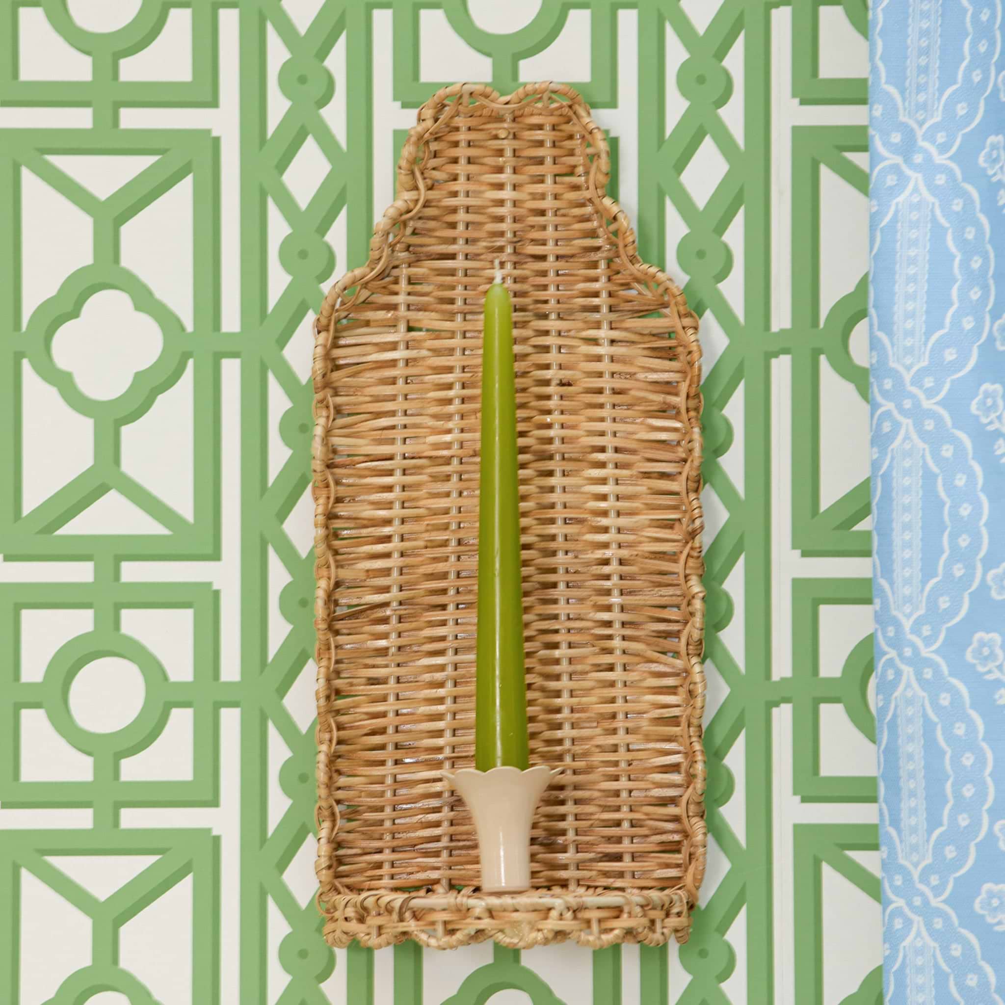 Wicker candle holder with a green candle on a decorative background
