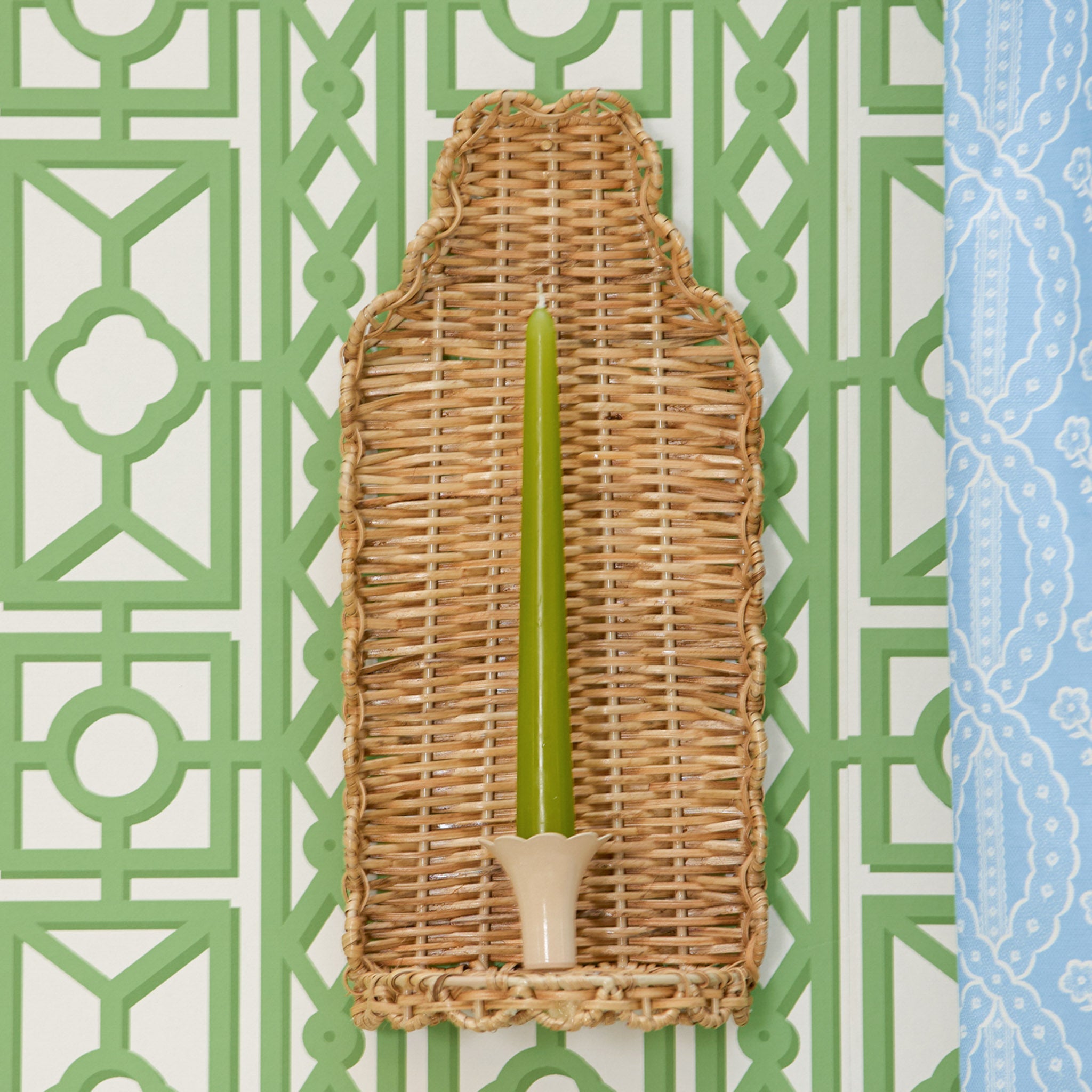 Wicker candle holder with a green candle on a decorative background