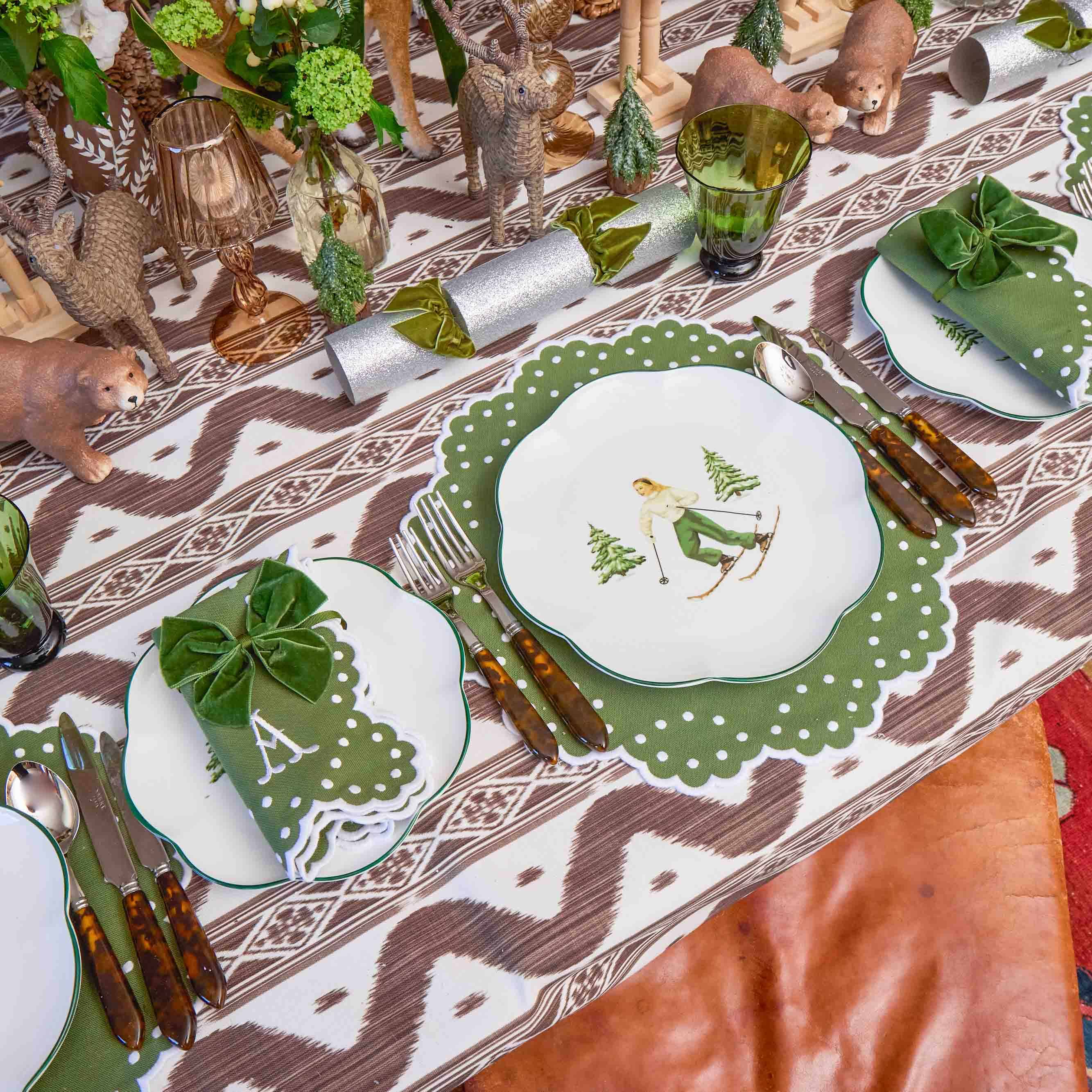 Decorative table setting with green glassware, and patterned tablecloth.