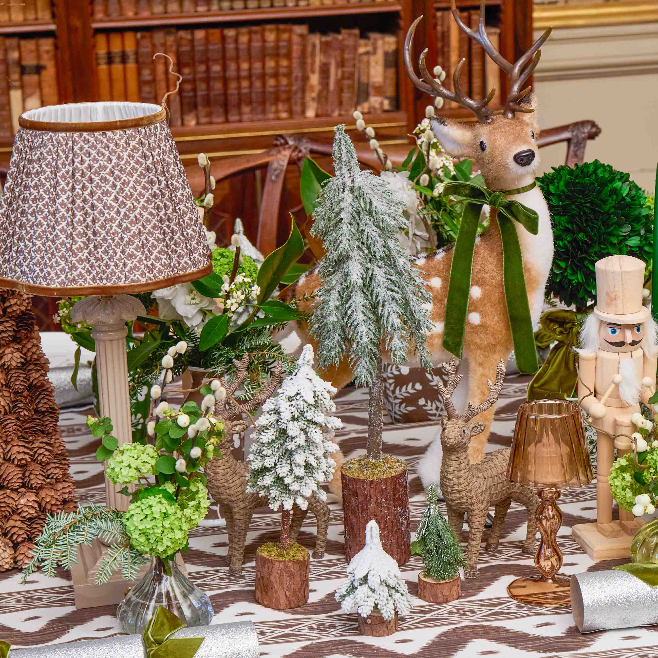 Decorative table setting with reindeer, trees, and a nutcracker in a room with wooden furniture.