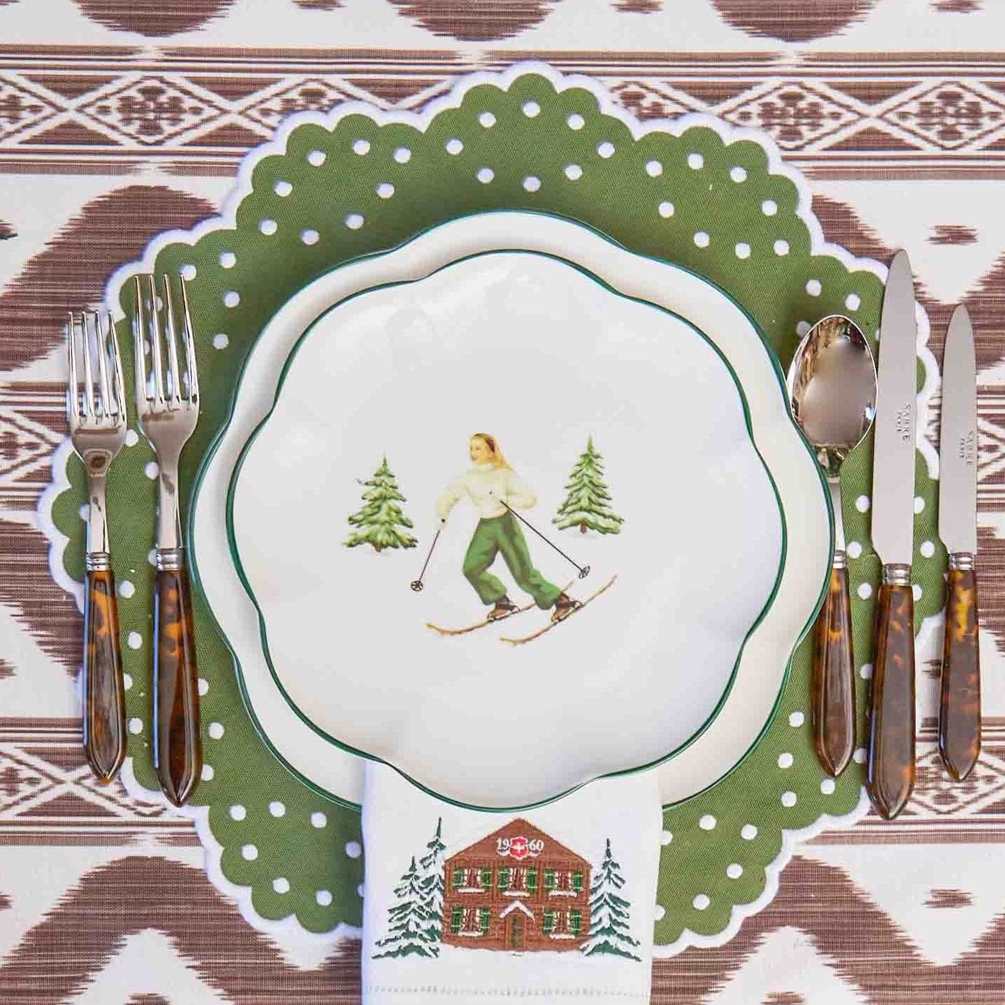 Placemat with winter-themed design featuring a skier and trees on a patterned tablecloth.