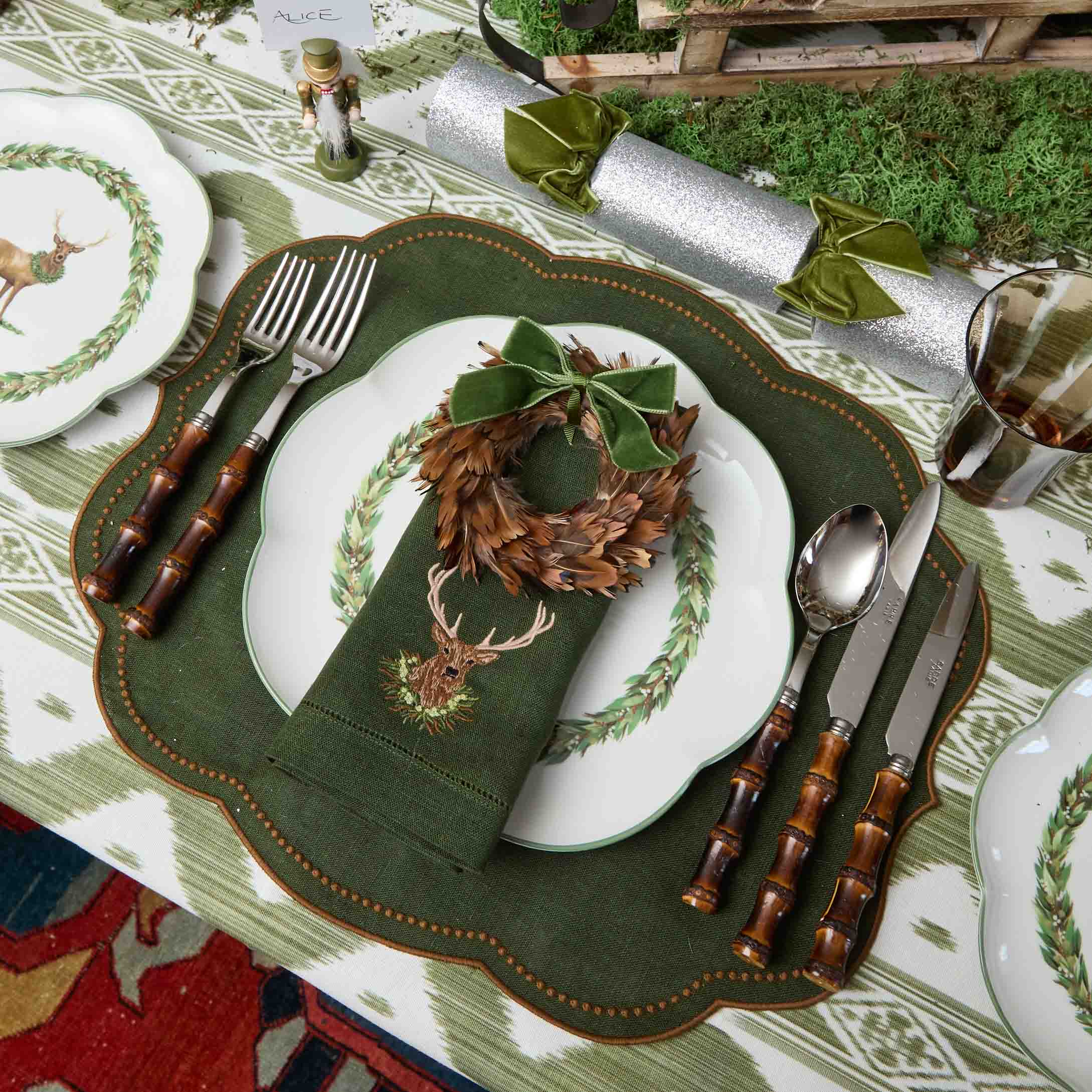 Decorative table setting with green placemat, plates, and cutlery on a patterned tablecloth.