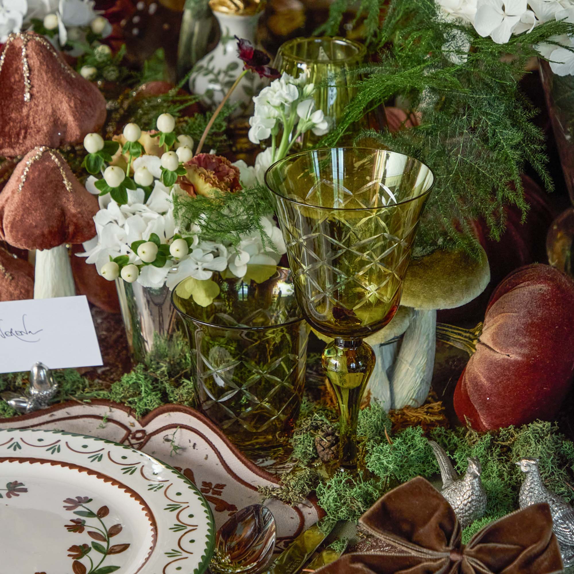 Decorative table setting with glassware, flowers, and autumn-themed decor.