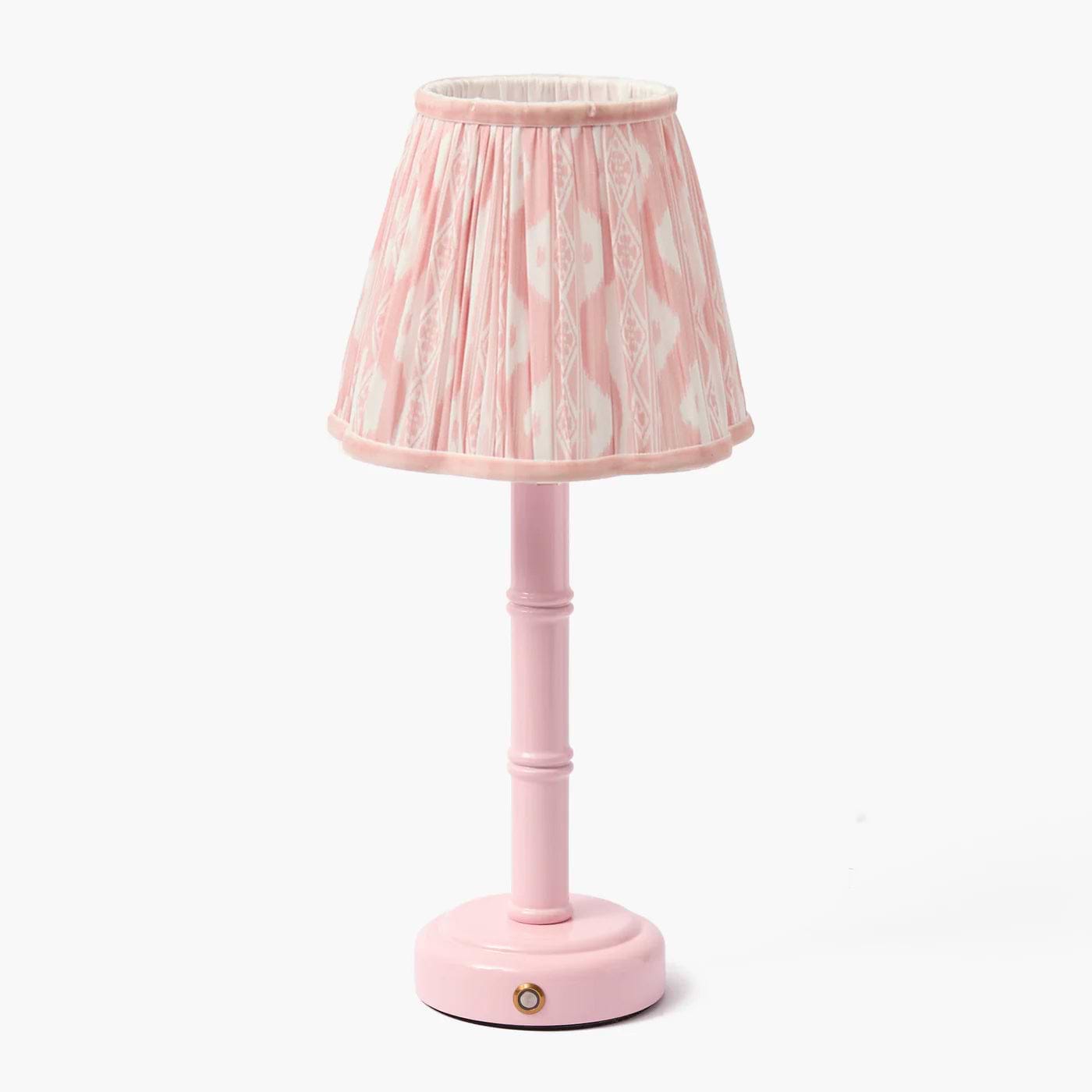 A pink lacquer rechargeable lamp with a bamboo-like design base and a pink ikat shade.