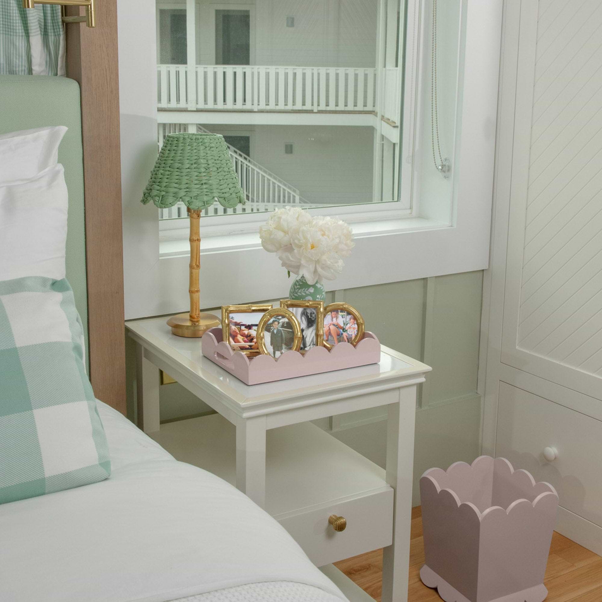 Bedroom with a nightstand, lamp, and decorative items near a window.