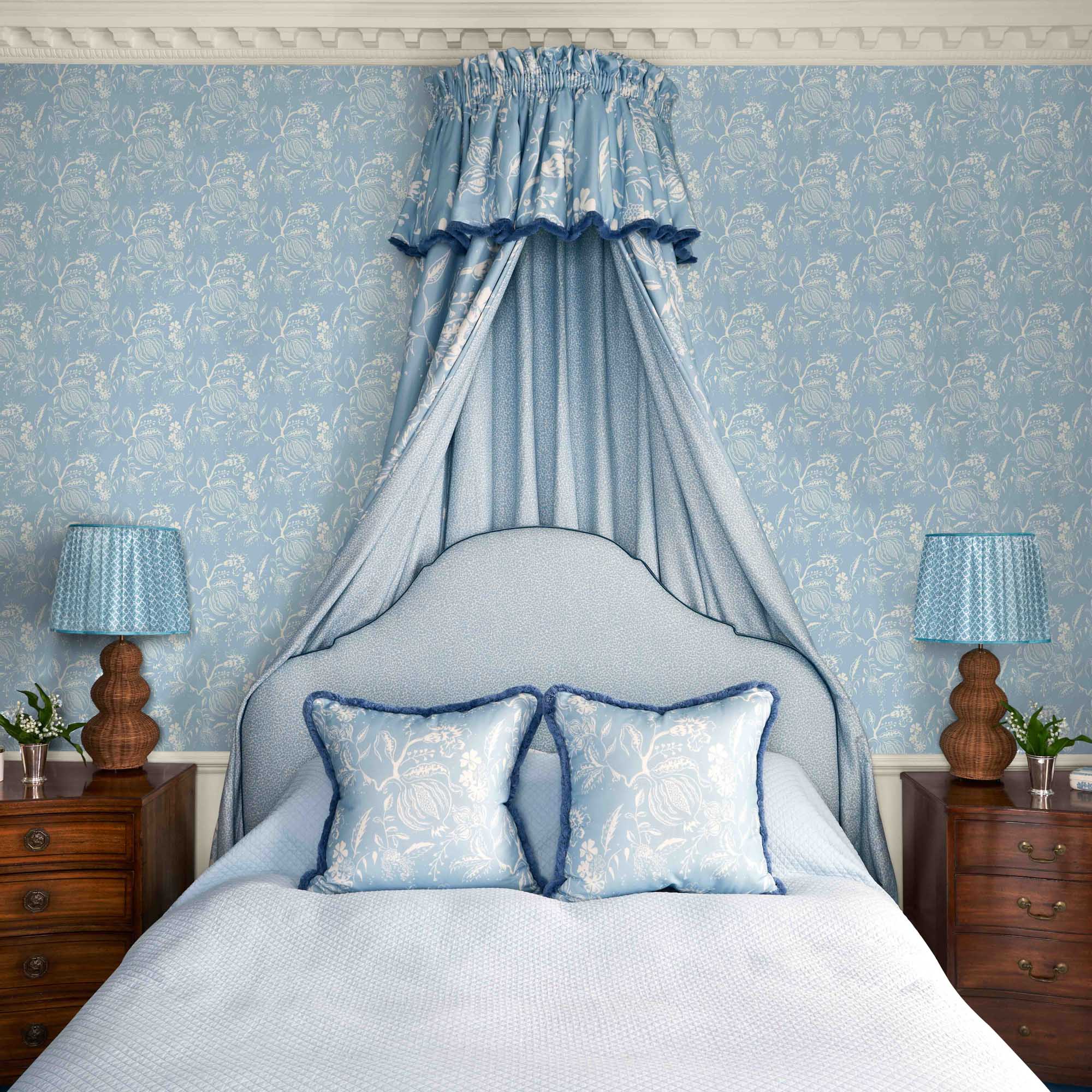 Bedroom with blue floral wallpaper, canopy, and matching lamps.