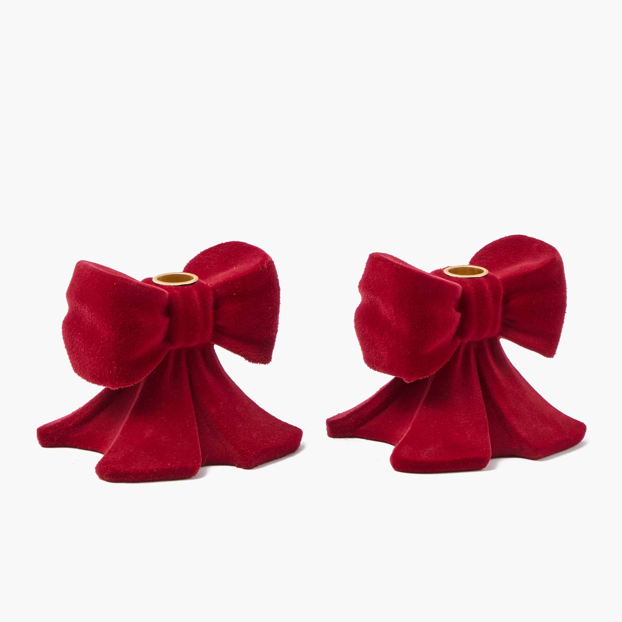 Two red velvet bow-shaped candle holders on a white background