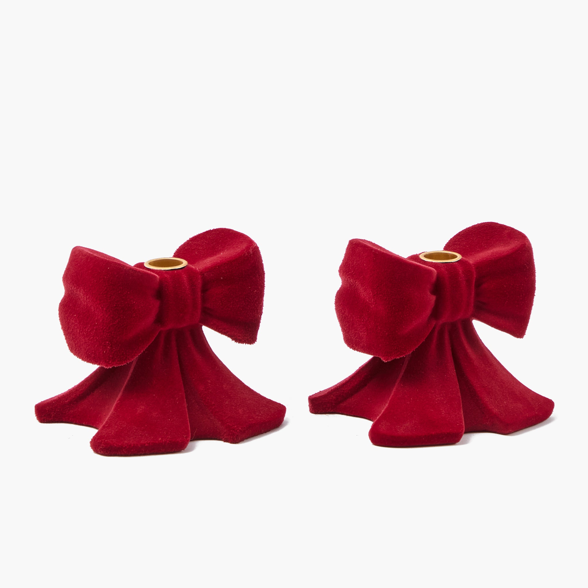 Two red velvet bow-shaped candle holders on a white background
