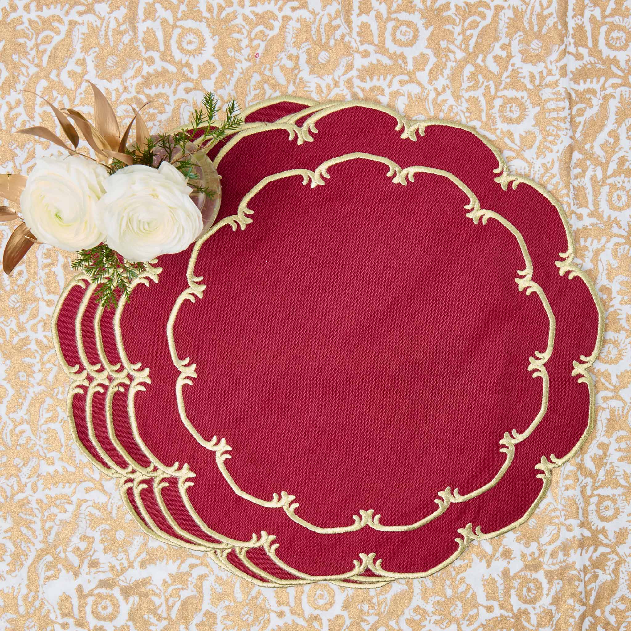 Set of red placemats with gold intricate designs on a decorative background
