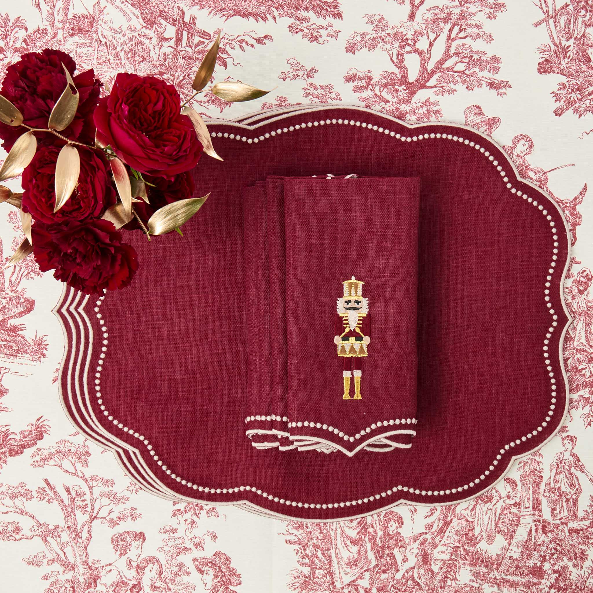 Red napkin with gold embroidery on a decorative plate with red floral design
