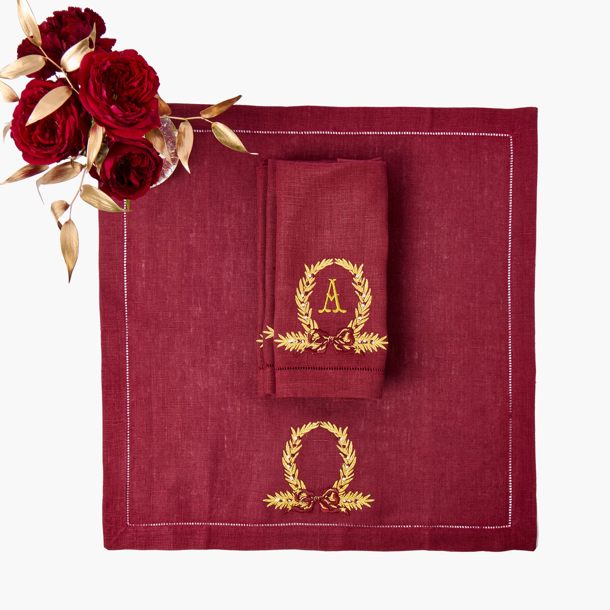 Red linen napkin with gold monogram design on a white background