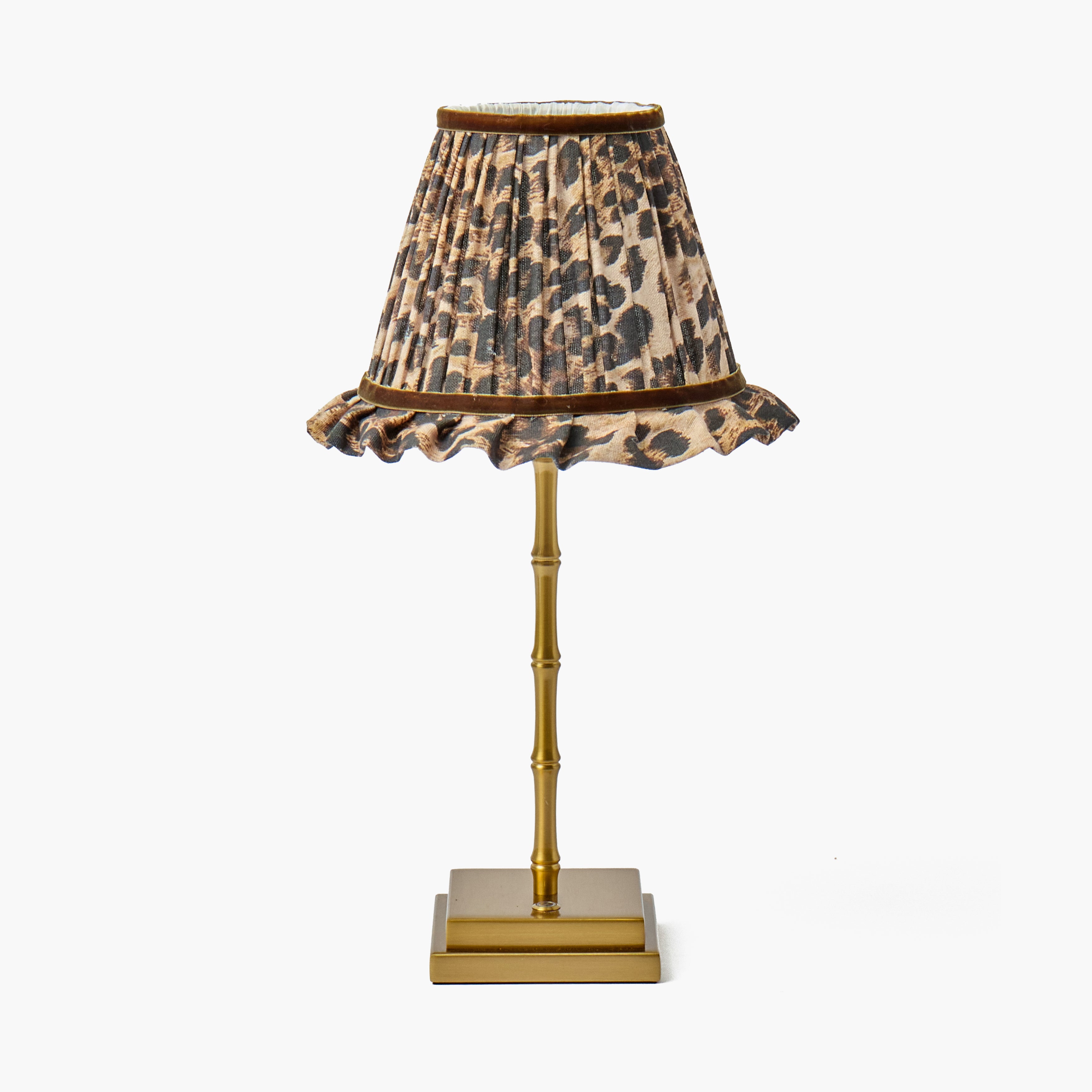 A table lamp with a pleated leopard-print shade and a glossy gold-finished bamboo-style stand on a plain white background.