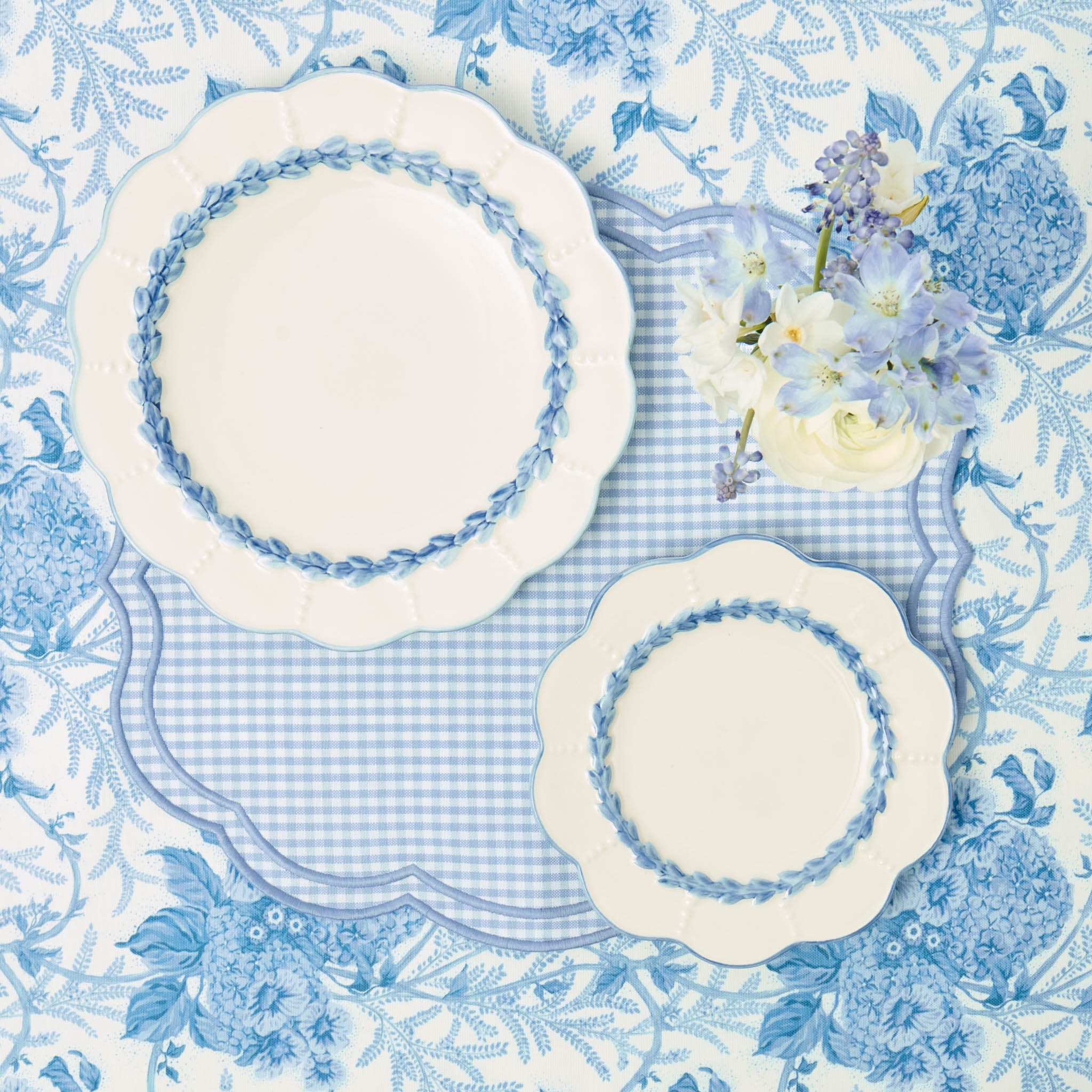 Set of white plates with blue floral patterns on a matching tablecloth.