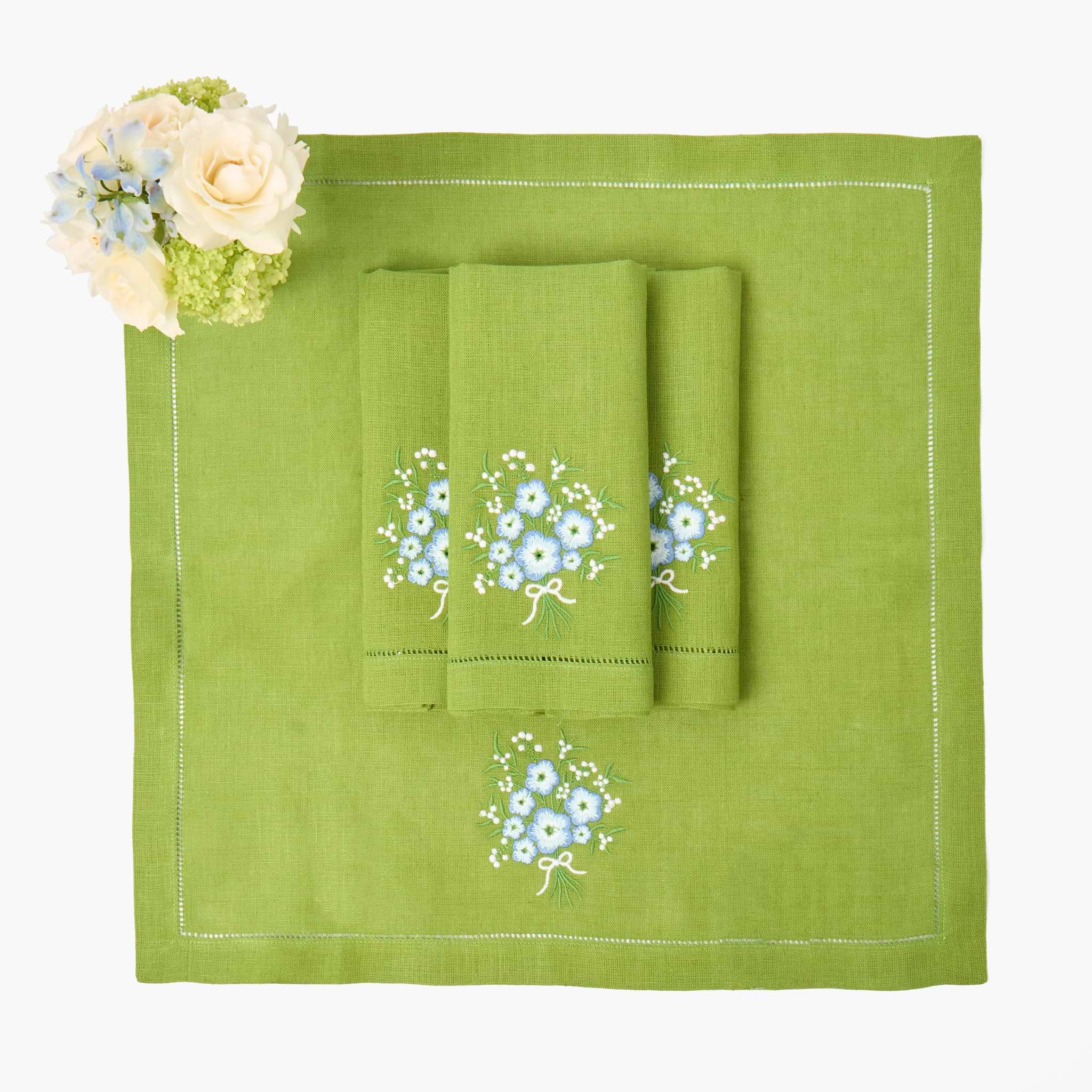 Green towel set with floral embroidery on a matching green placemat.