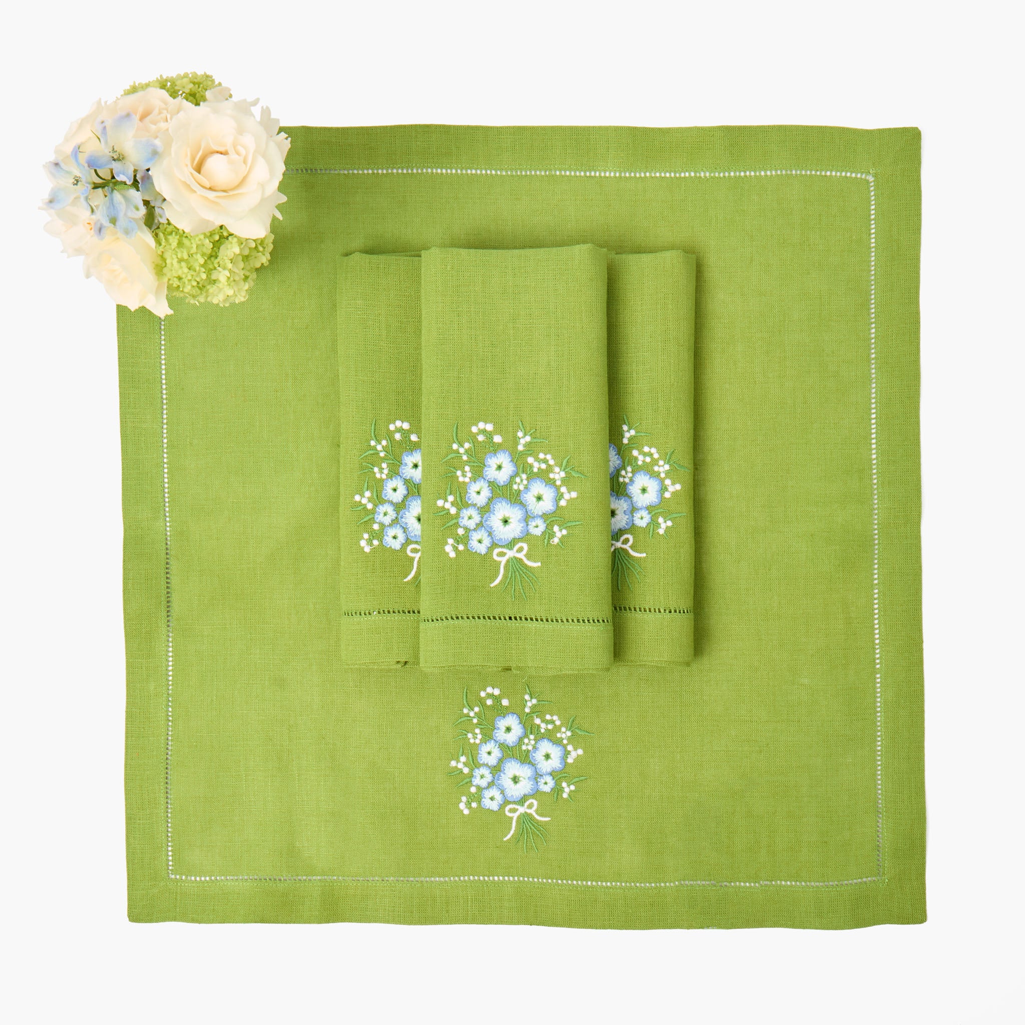 Green towel set with floral embroidery on a matching green placemat.