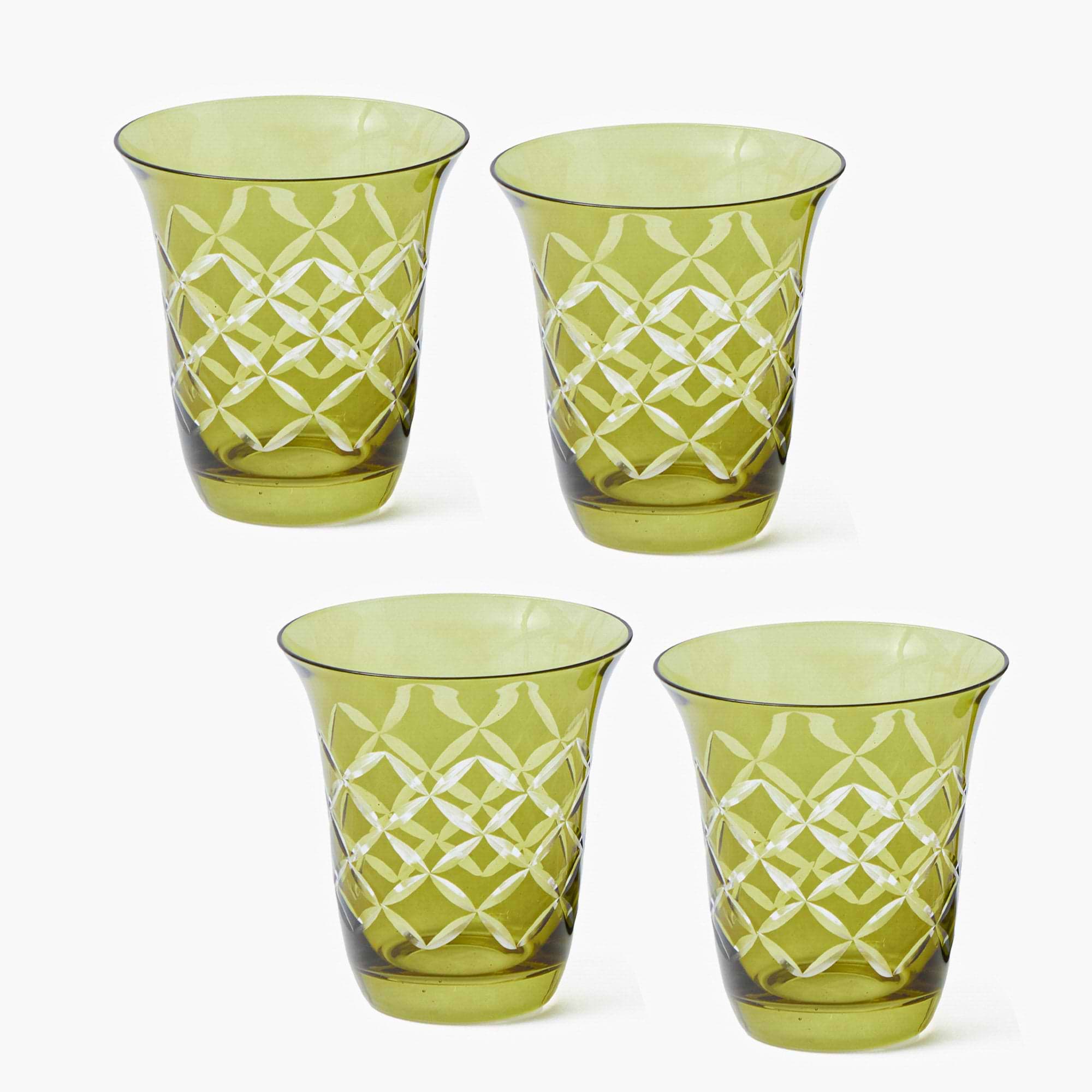 Four green glass tumblers with white geometric patterns on a white background