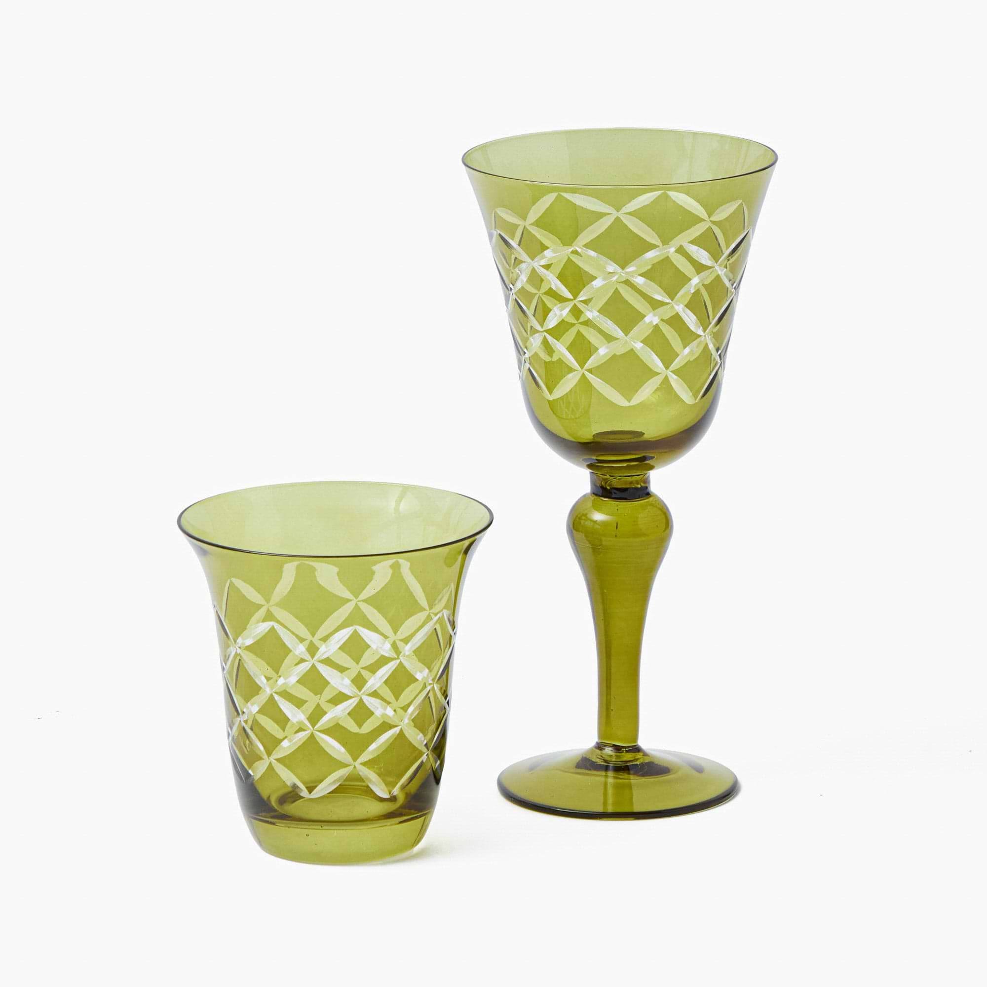 Two green glass tumblers with white geometric patterns on a white background