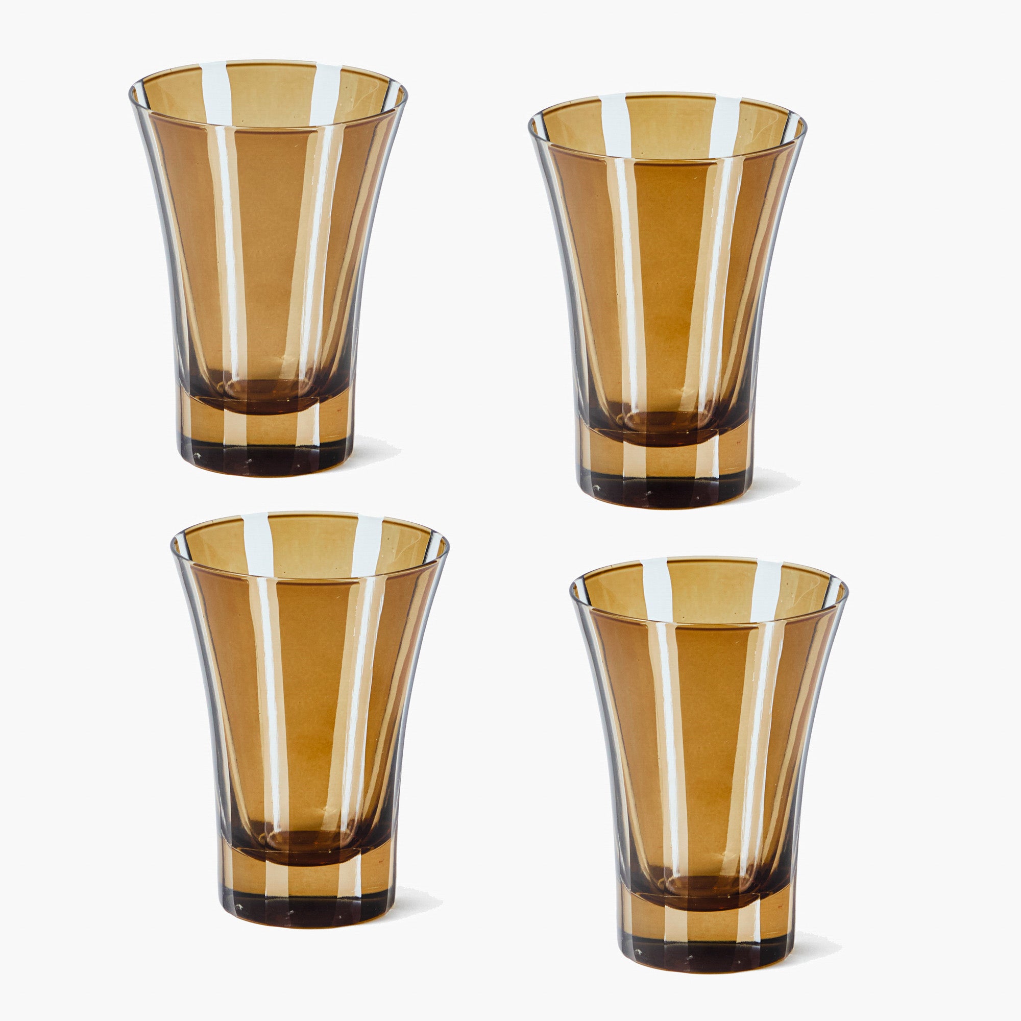 Four amber-colored glass tumblers on a white background