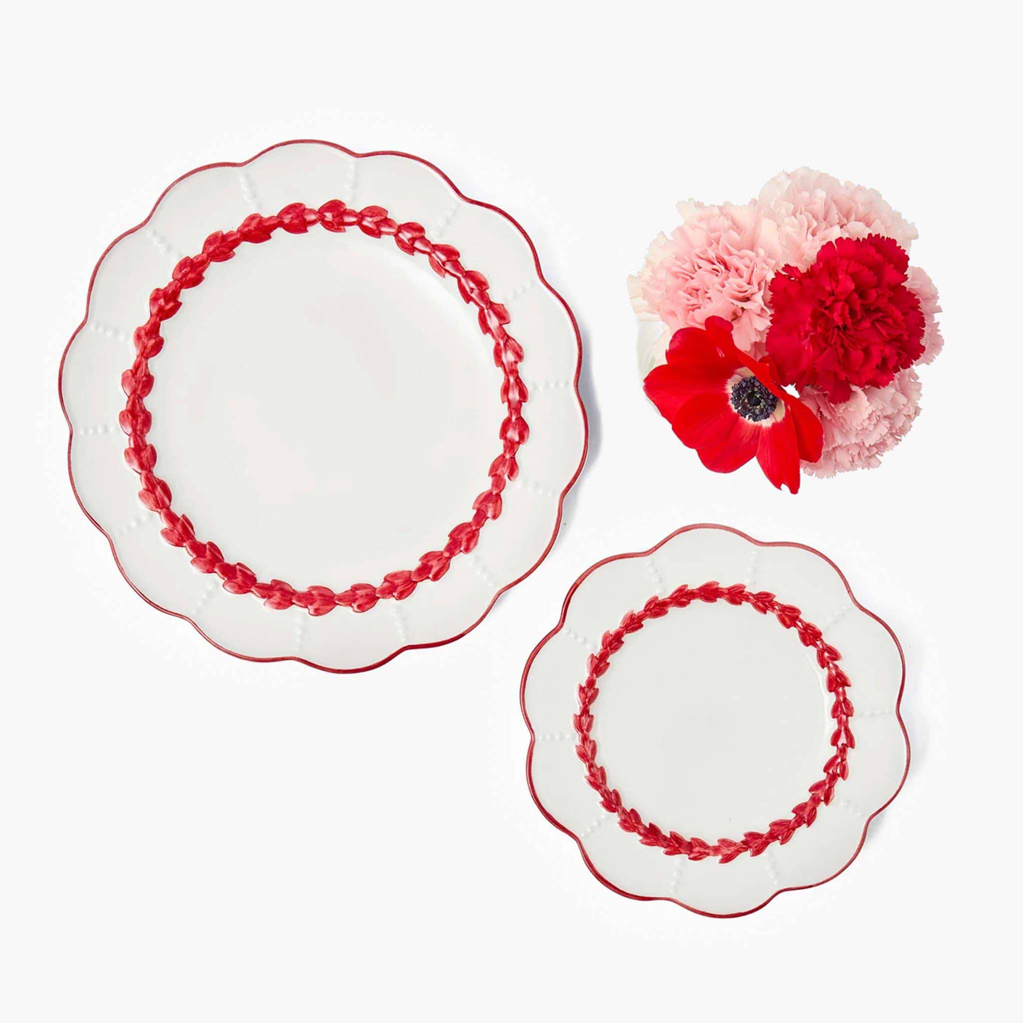 Two decorative plates with red floral patterns and a bouquet of pink and red flowers on a white background.
