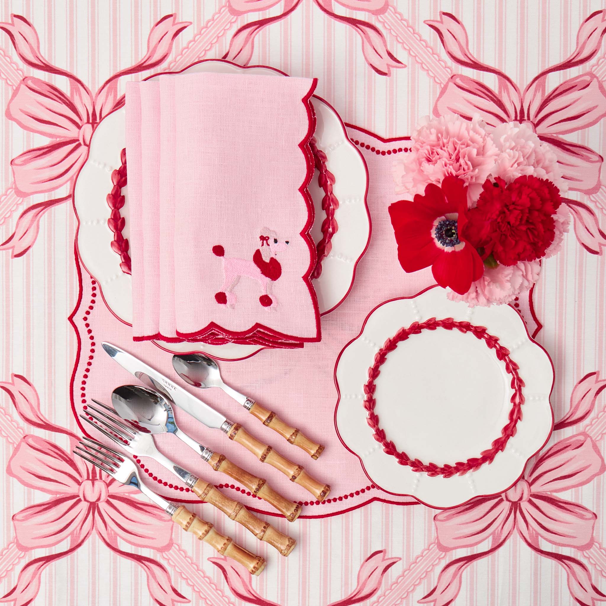 Pink and white place setting with decorative elements on a matching pink tablecloth.