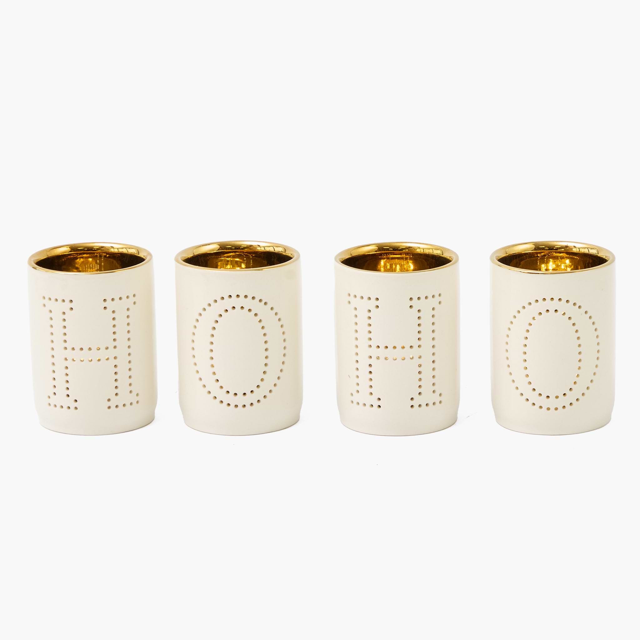 Four tealight cups with gold rims and lettering on a white background