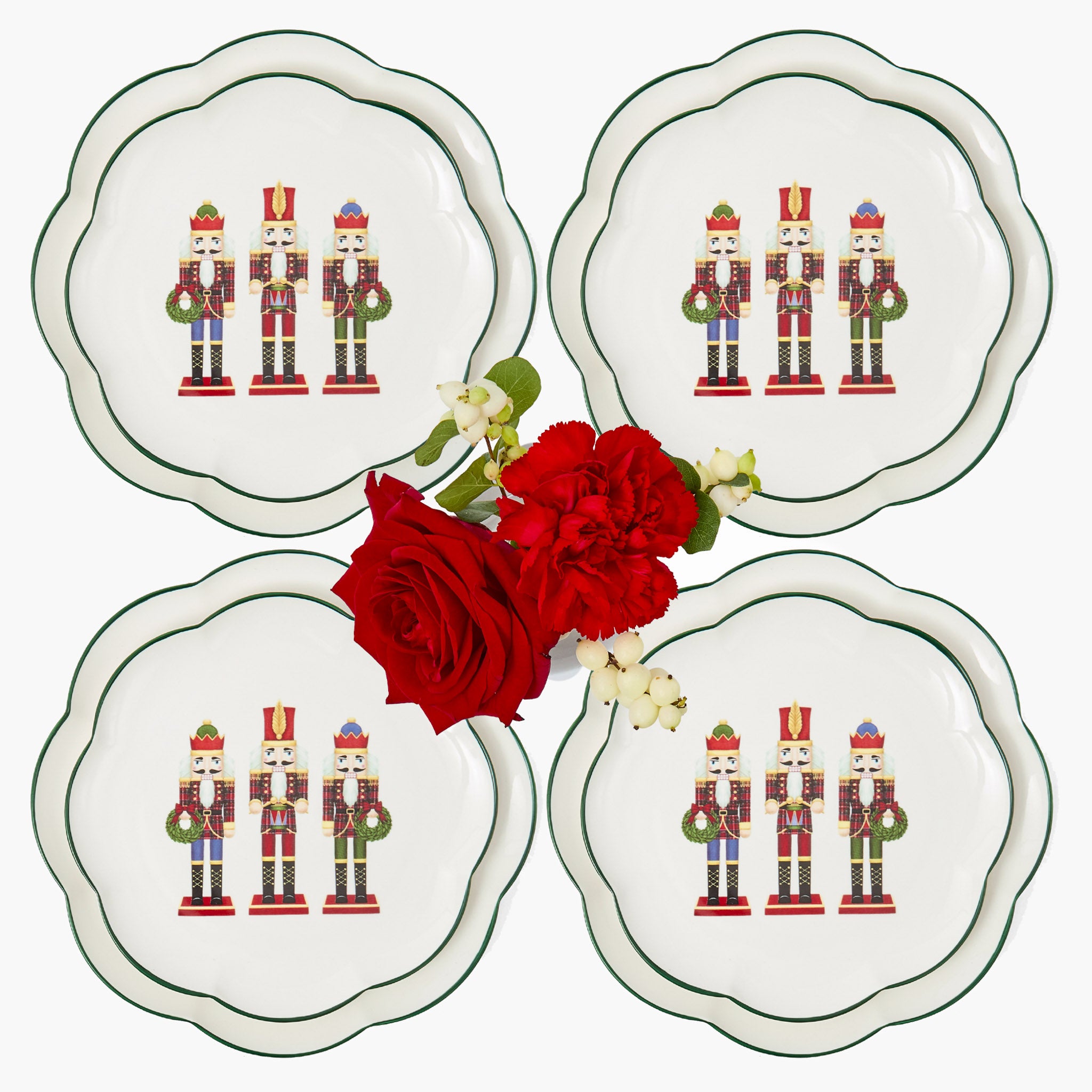 Four decorative plates with nutcracker design and a red rose on a white background