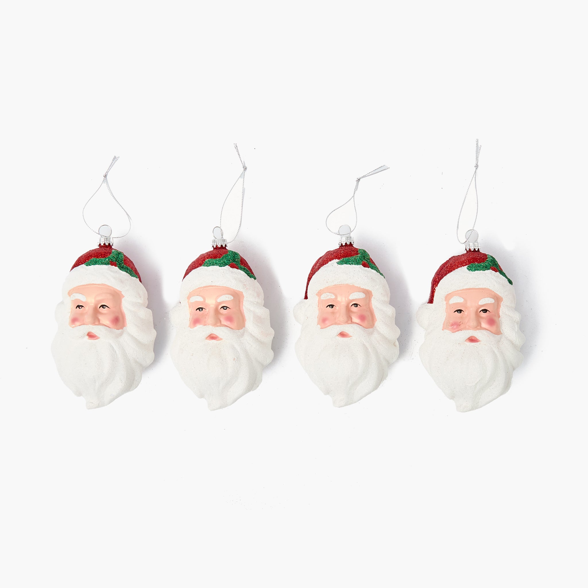 Four Santa Claus face ornaments hanging against a white background