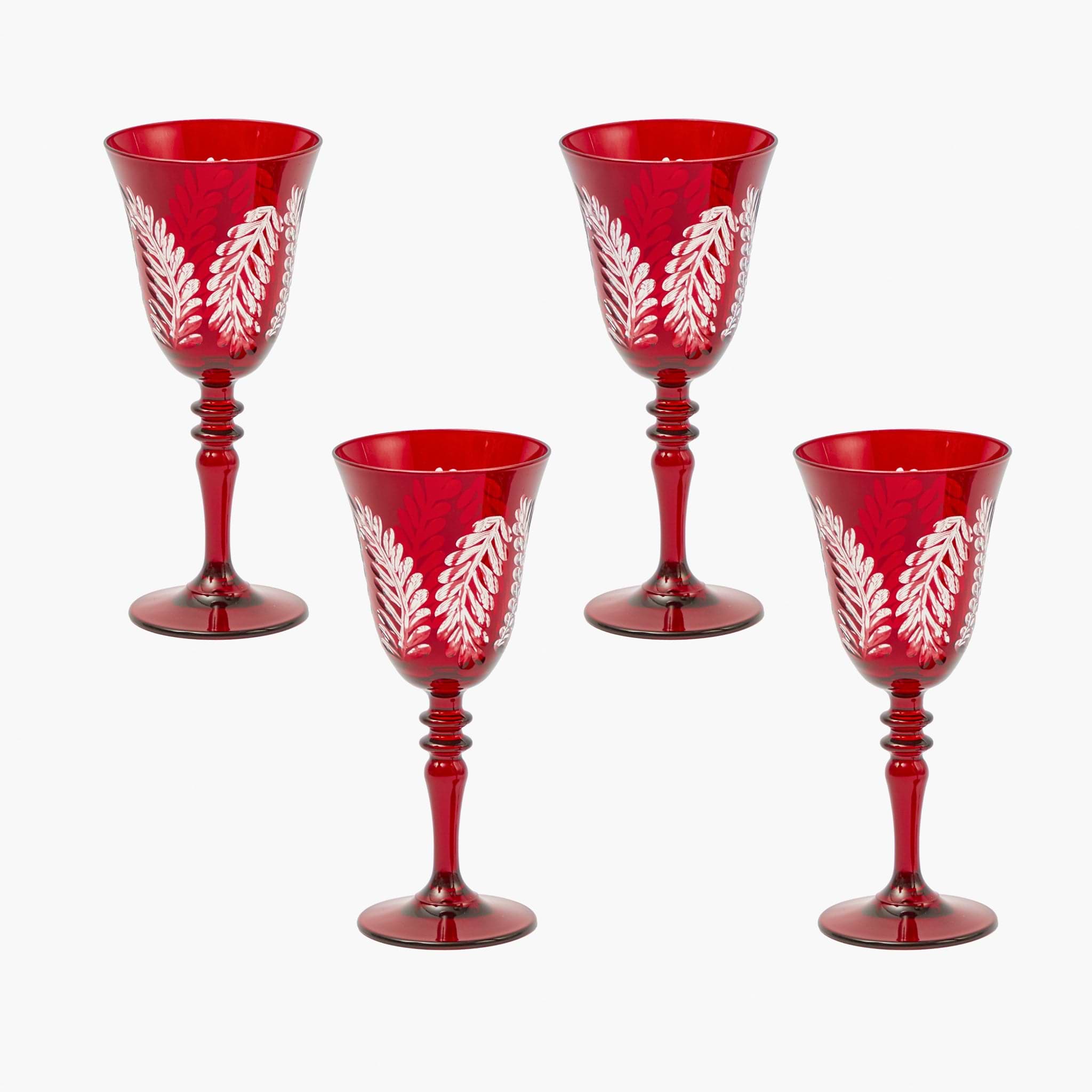Set of four red wine glasses with white leaf patterns on a white background