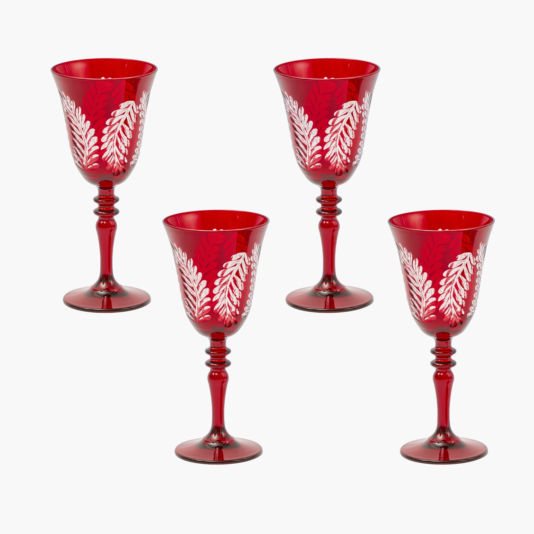 Set of four red wine glasses with white leaf patterns on a white background