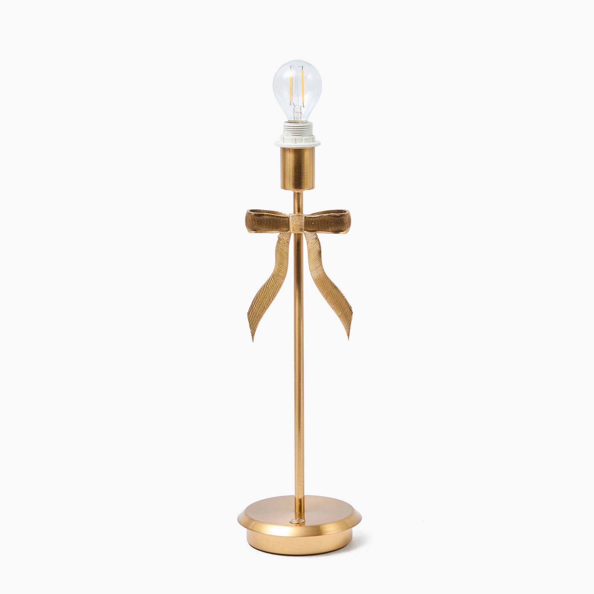 Gold table lamp with a decorative bow on a white background