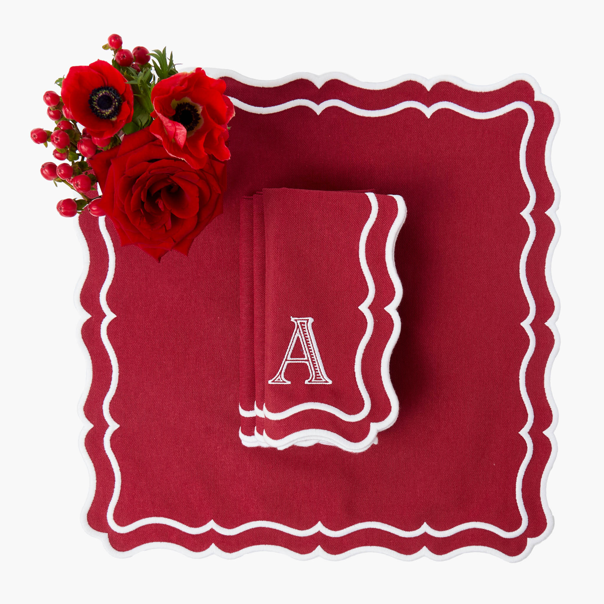 Red Napkin with white monogram option  accompanied by red flowers on a white background.