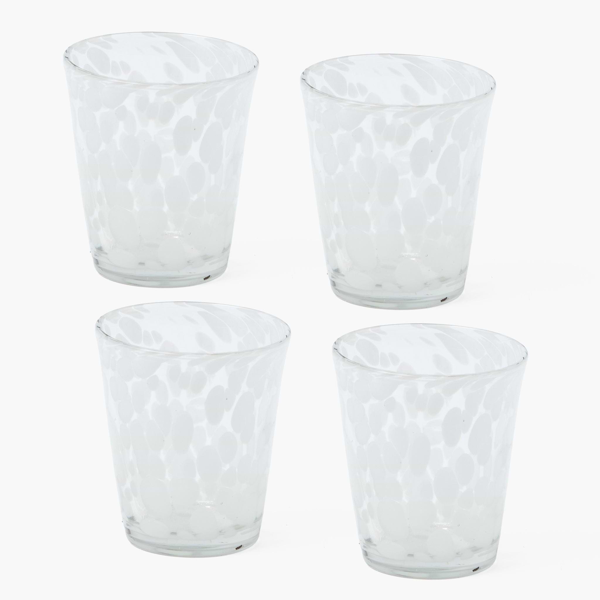 Four clear glass tumblers with textured design on a white background
