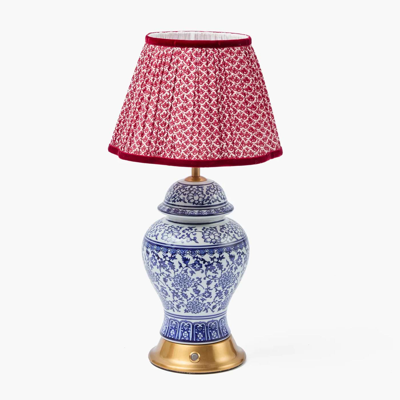 Decorative lamp with a red patterned shade on a white background