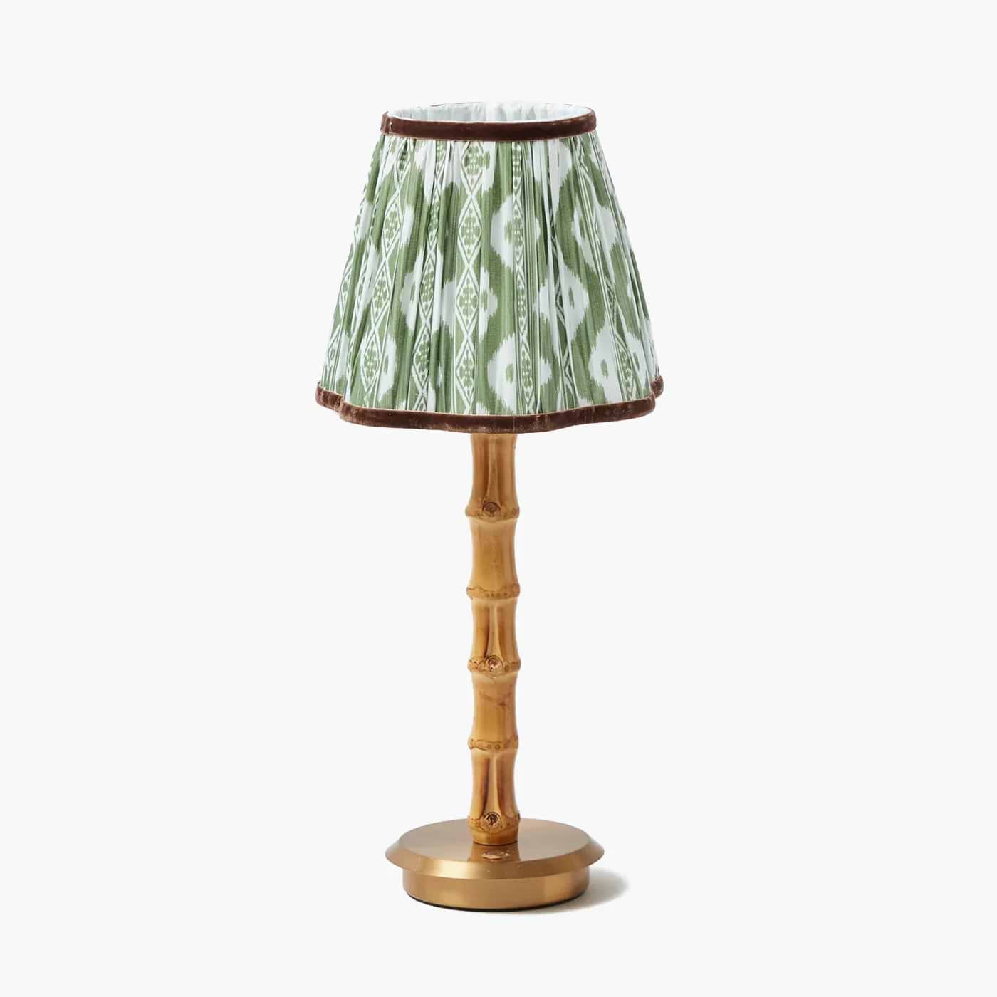 Small lamp with a green ikat patterned shade and gold base on a white background